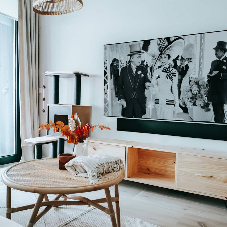 Zona de estar con mueble de televisor de madera, cortinas beige y lámapra de fibras por Ana Villamañan
