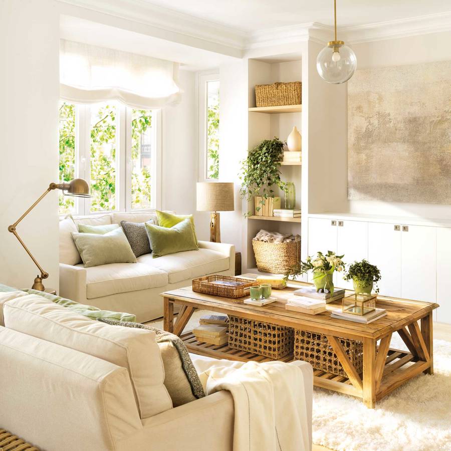 Salón con dos sofás beiges, mesa de centro rústica de madera y librería blanca.