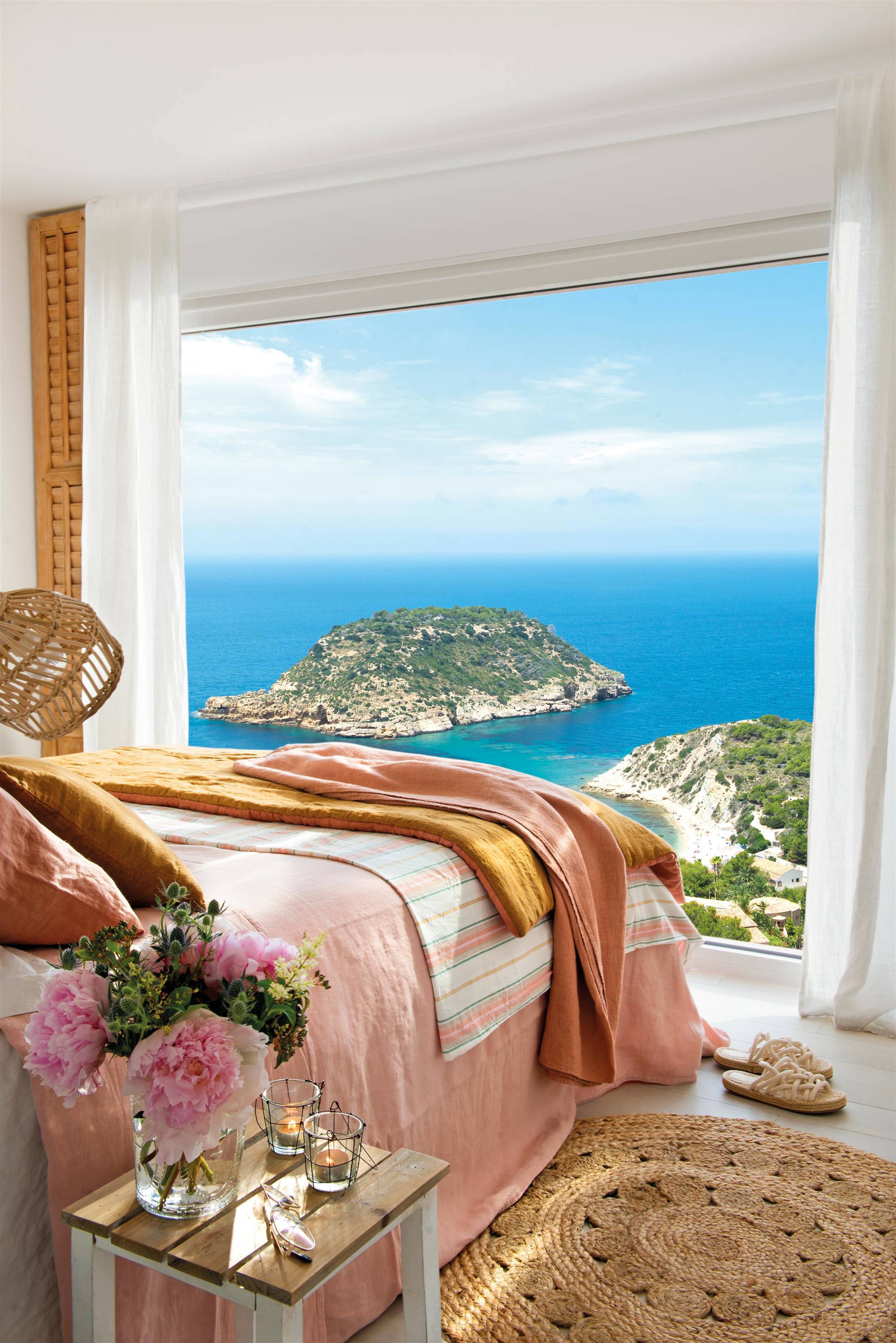 Dormitorio con ventanal y vistas al mar frente a la cama.