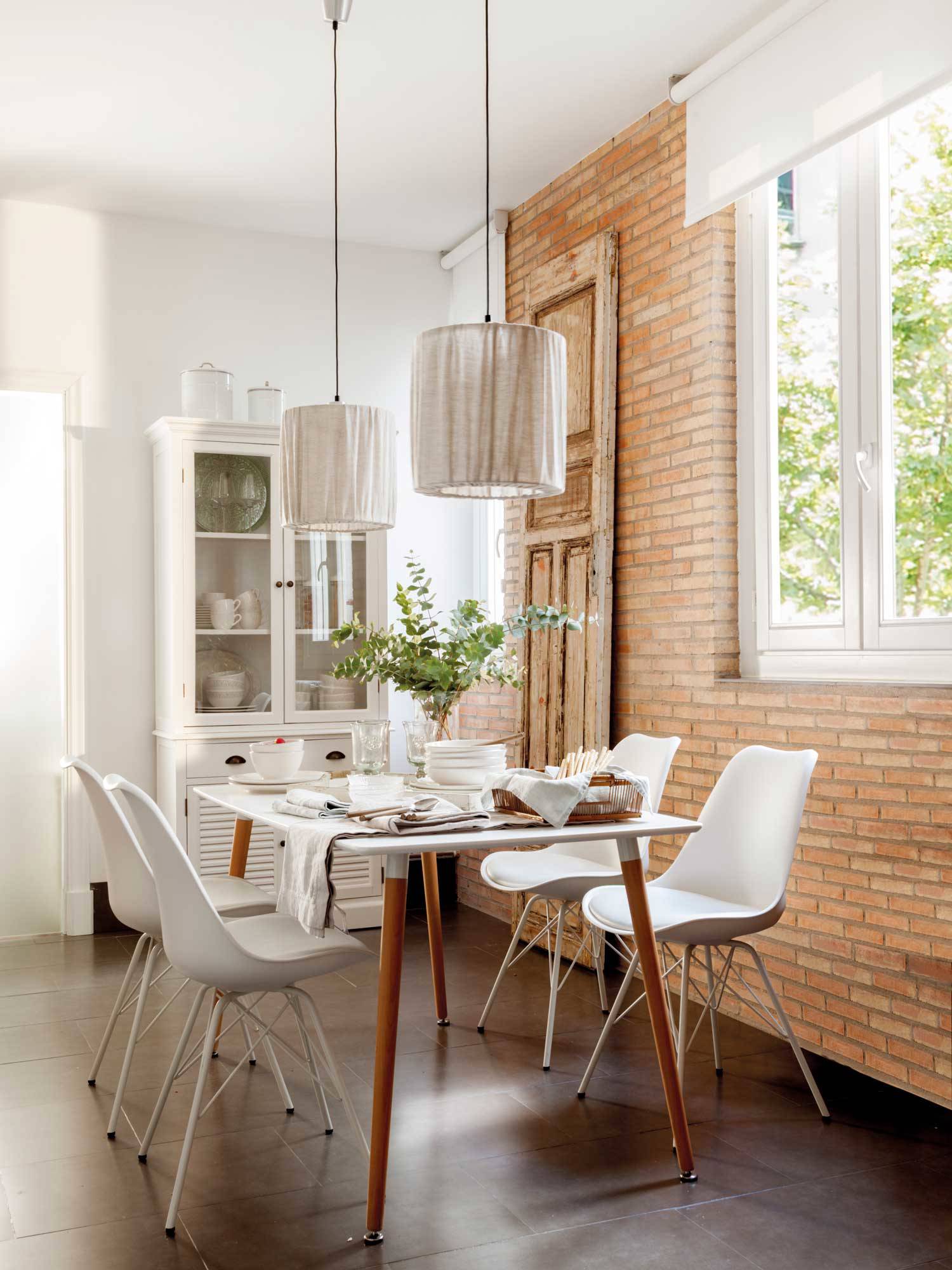Comedor con pared de ladrillo, vitrina pintada en blanco, mesa y sillas.