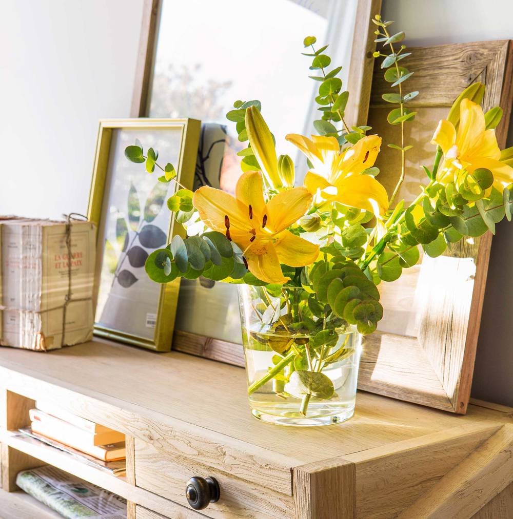 Detalle de jarrón con flores en aparador de madera
