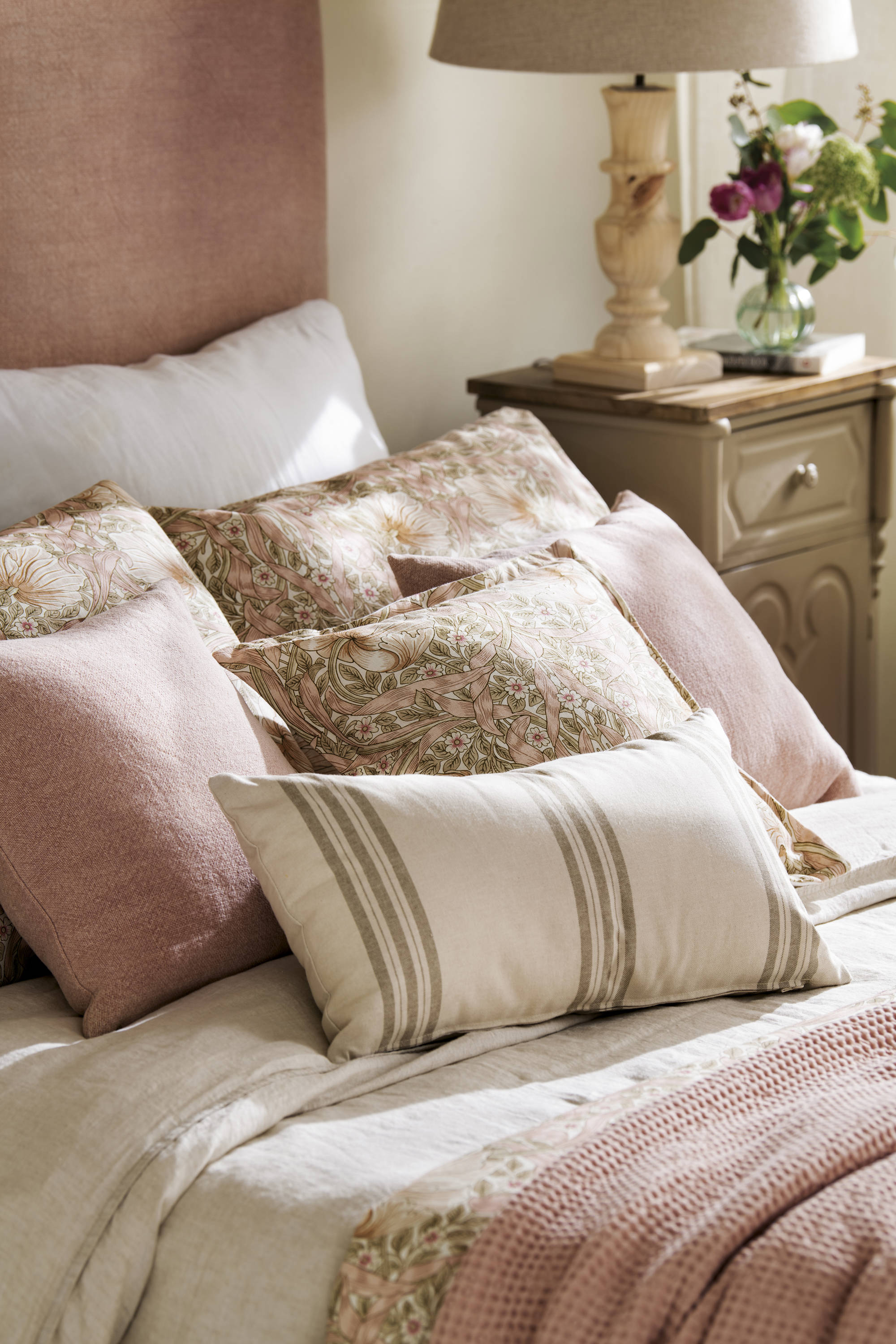 Dormitorio con ropa de cama rosa y cojines