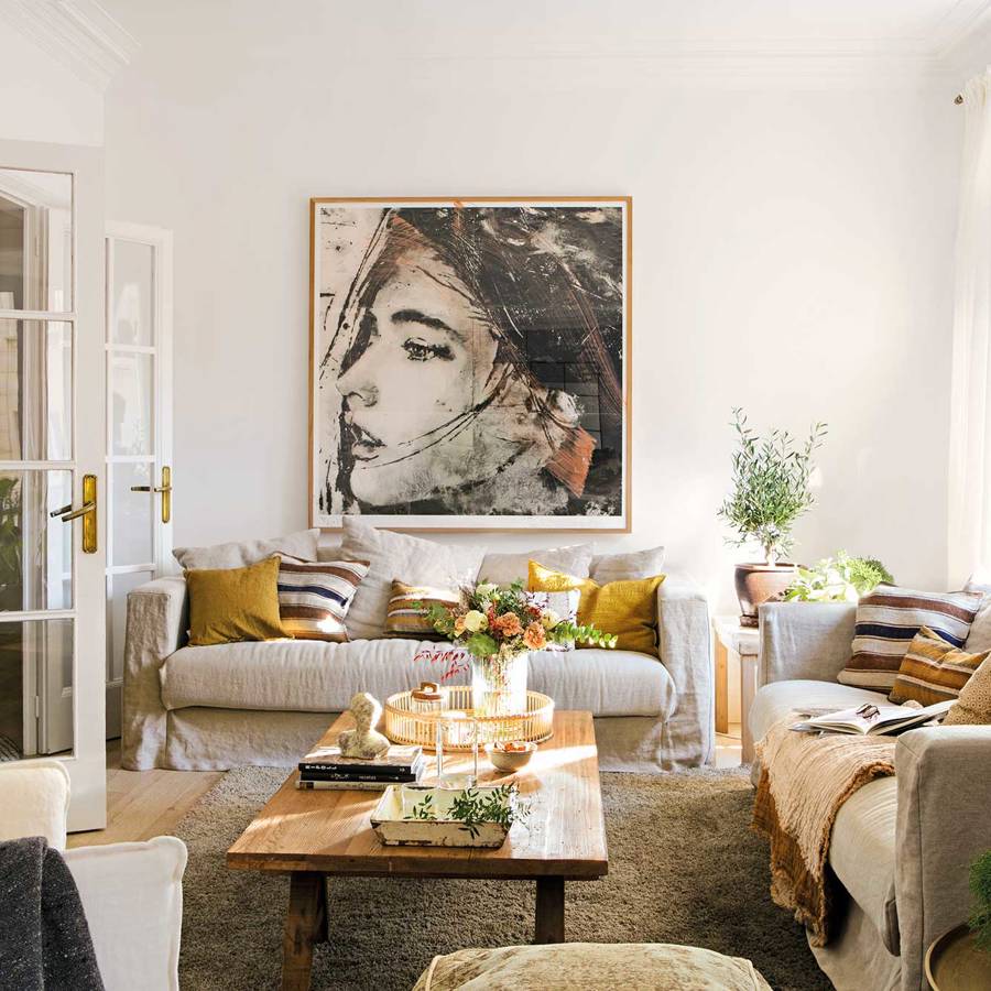 Salón clásico-moderno con sofás de lino beige, mesa de centro de madera y cuadro en la pared.