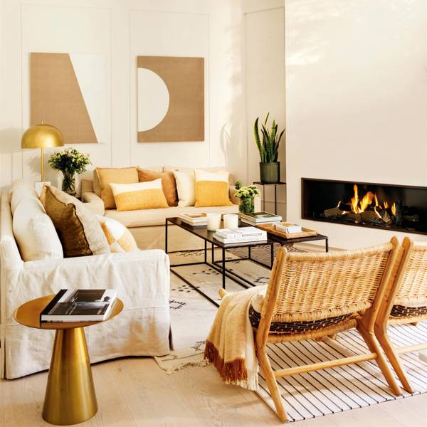 Salón clásico-moderno con dos sofás de lino, butacas de fibras, mesa auxiliar de latón y chimenea.