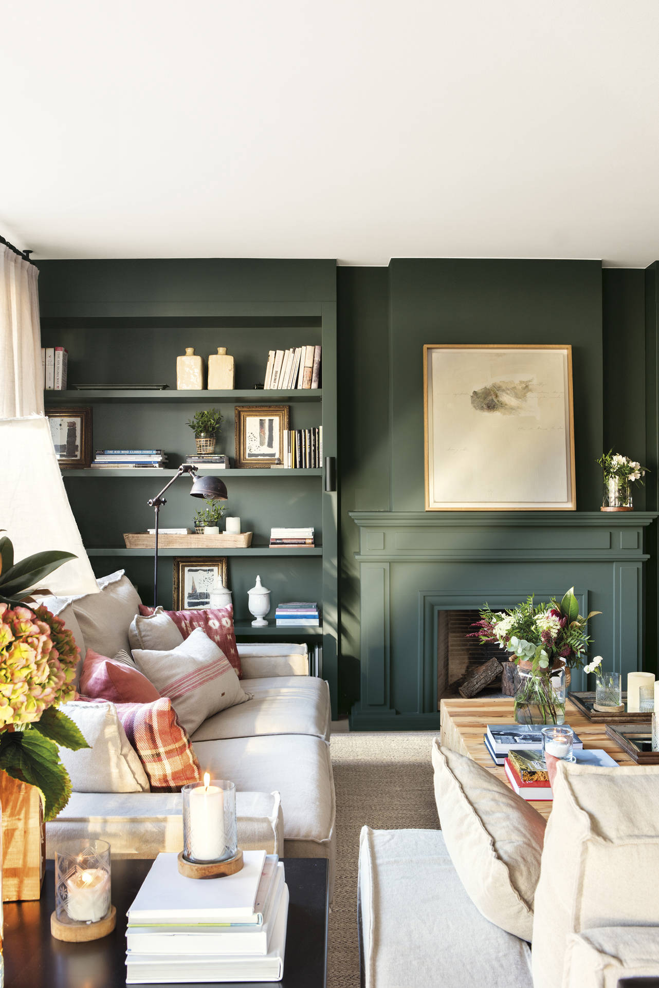Salón con chimenea y librería pintadas de color verde.