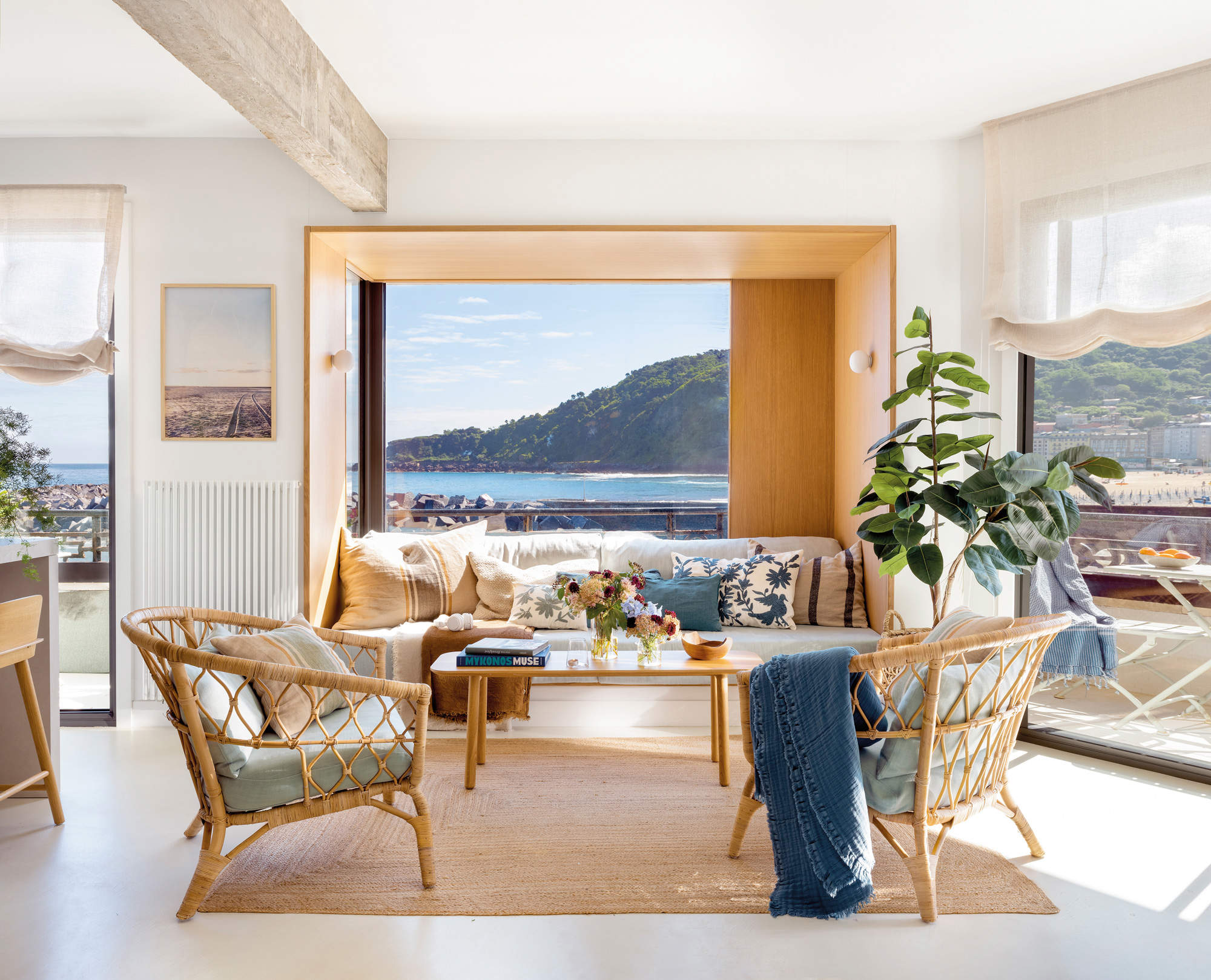 Salón con vistas al mar, con sofá de obra y dos sillones de fibra.