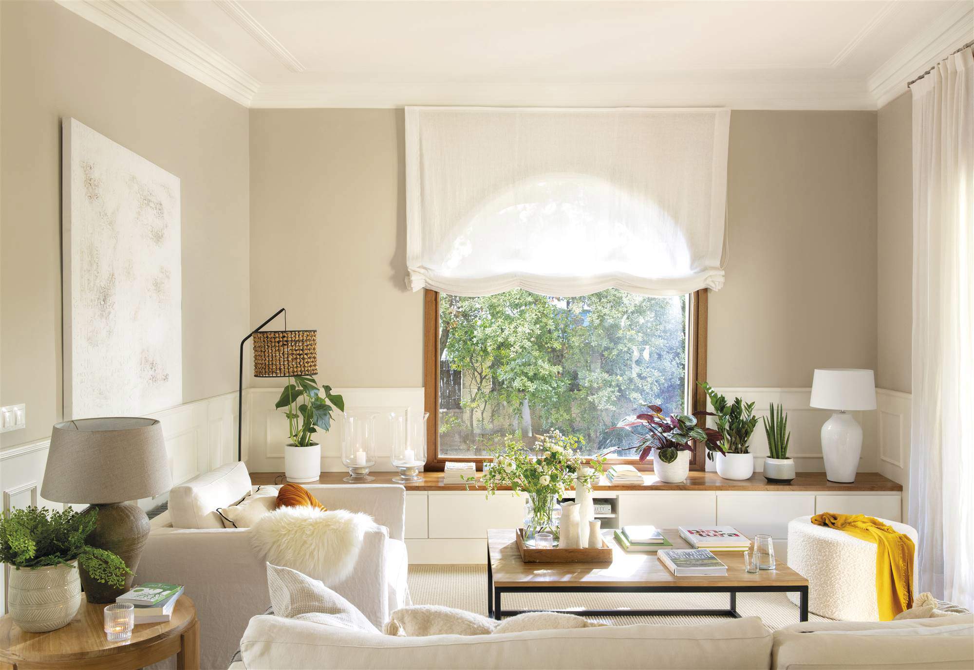 Un salón blanco y gris con mueble a medida bajo la ventana.