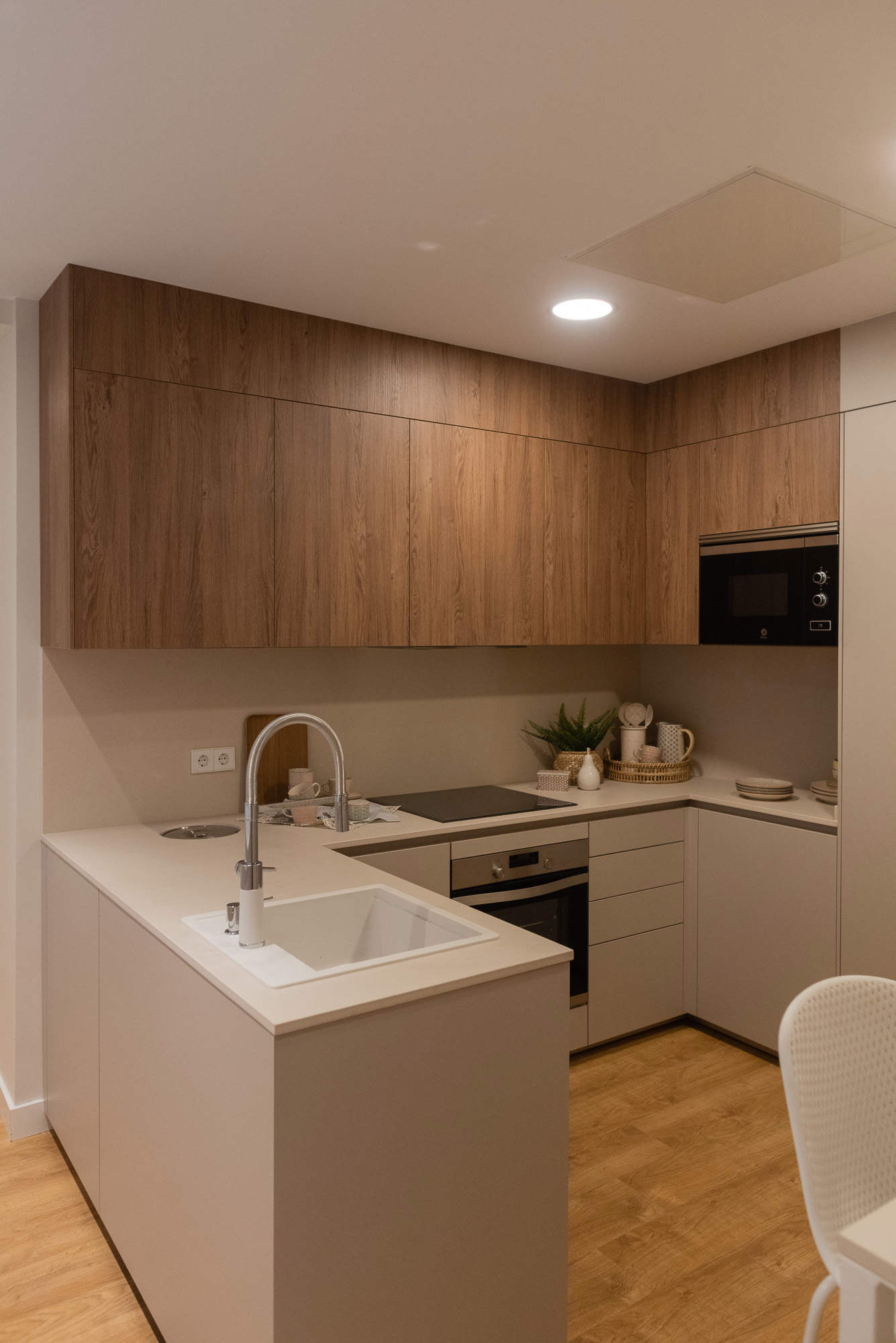 Cocina abierta con barra, muebles superiores de madera y frentes lisos por Deco Living
