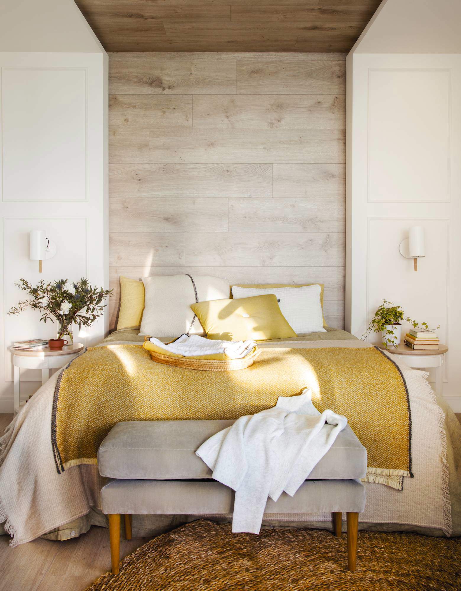 Dormitorio con cabacero de madera hasta el techo y ropa de cama mostaza. 