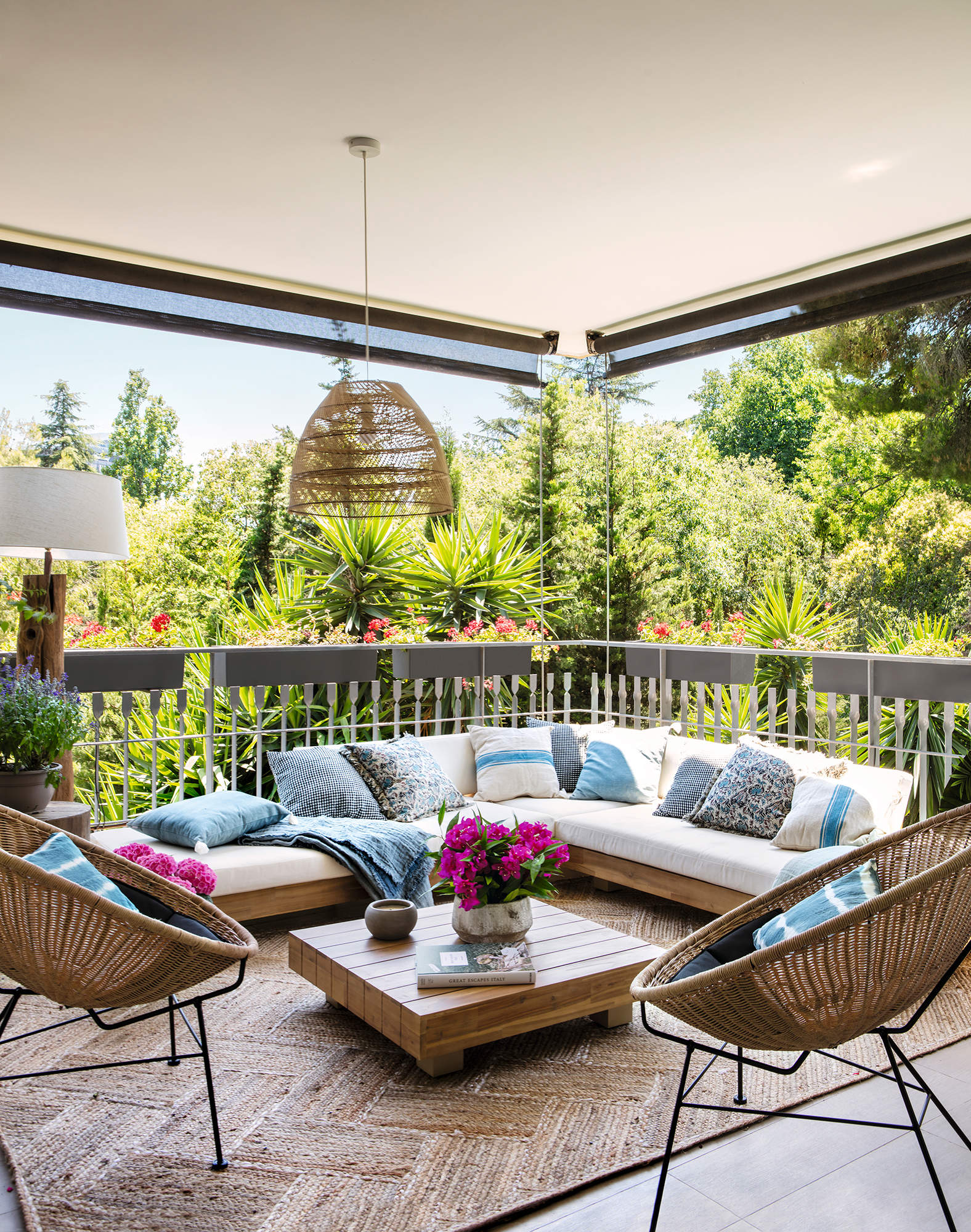 Terraza con encanto con sofá de madera, cojines blancos y azules y alfombra de fibras00564429