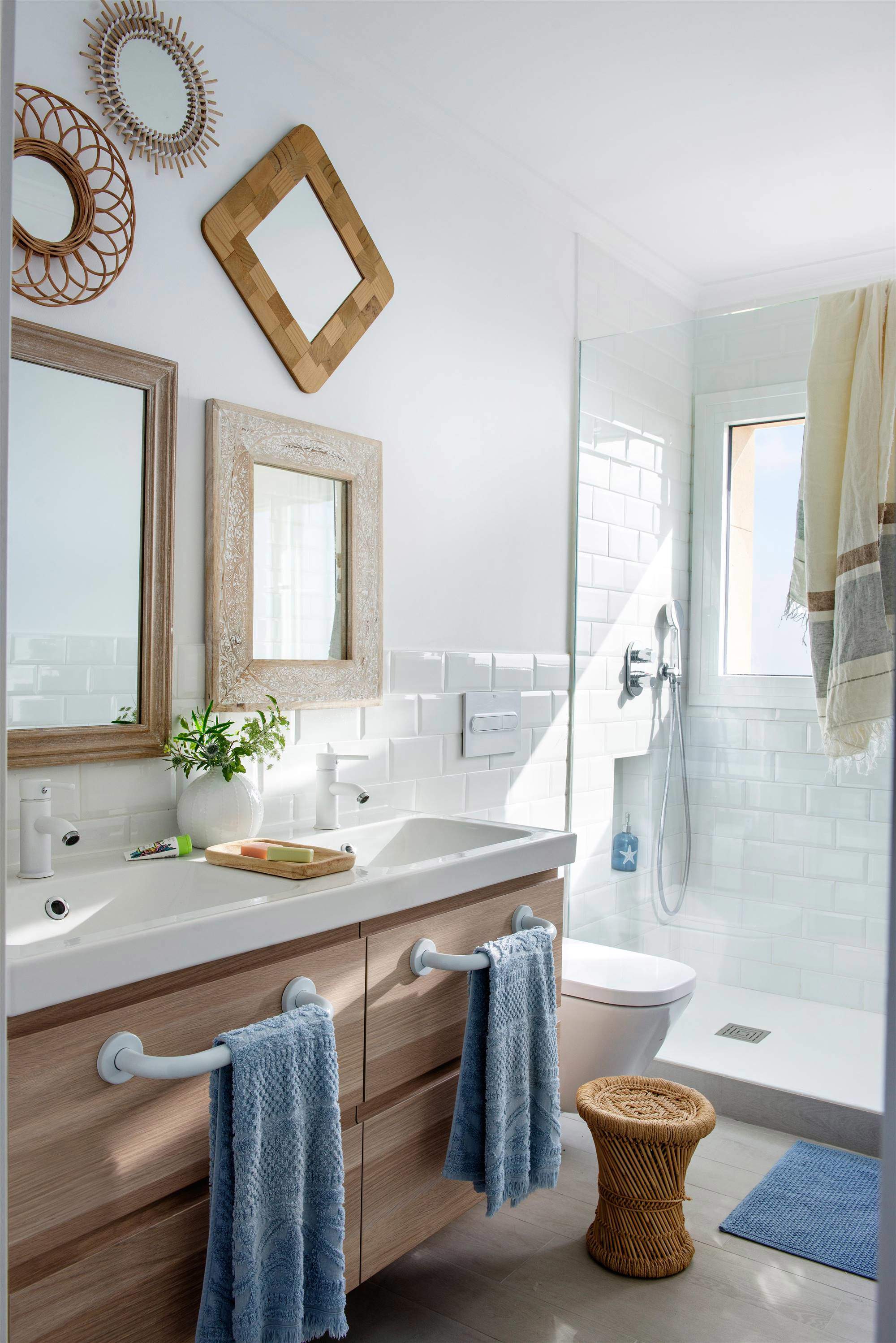 Pared del baño decorada con espejos de formas y tamaños diferentes.