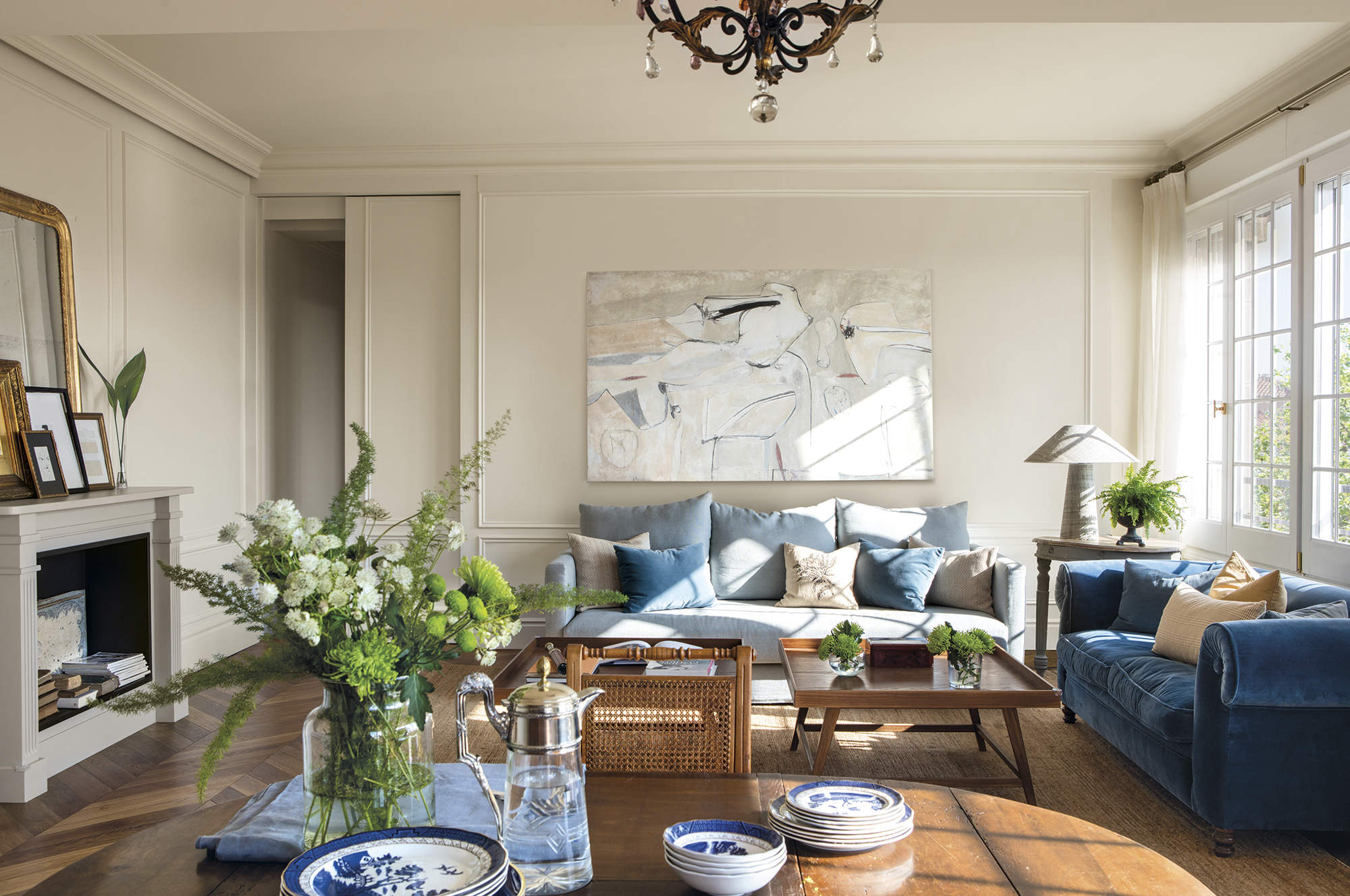 Salón clásico con sofás azules, cuadro XXL y chimenea