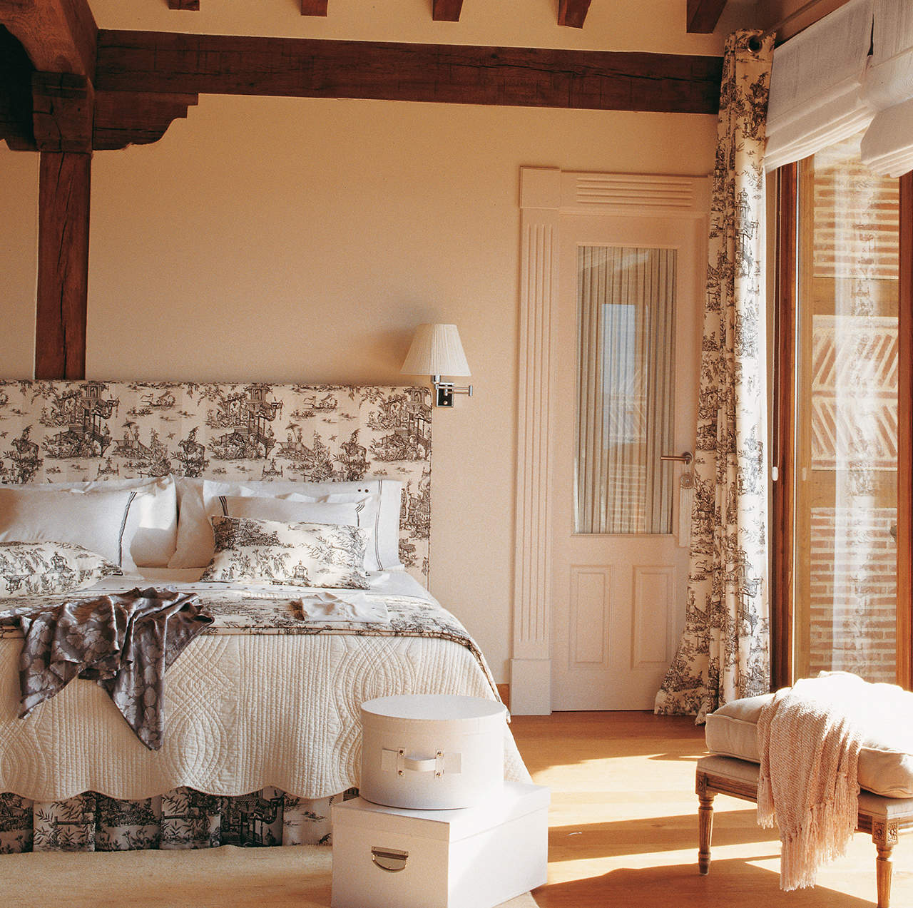 Dormitorio con cabecero, ropa de cama y cortinas con telas con el mismo toile de jouy