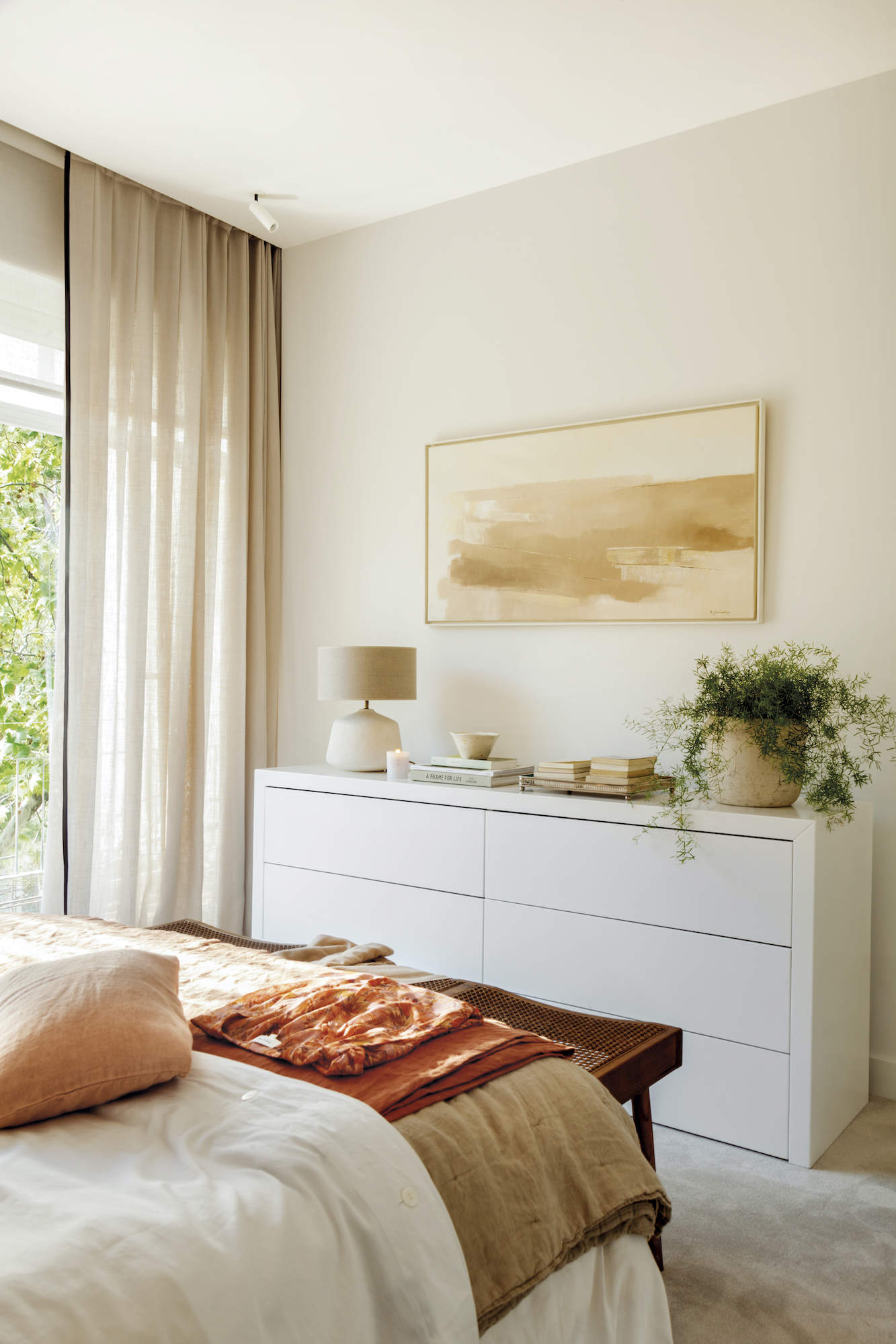 Dormitorio con cómoda blanca y cuadro en la pared frente a la cama.