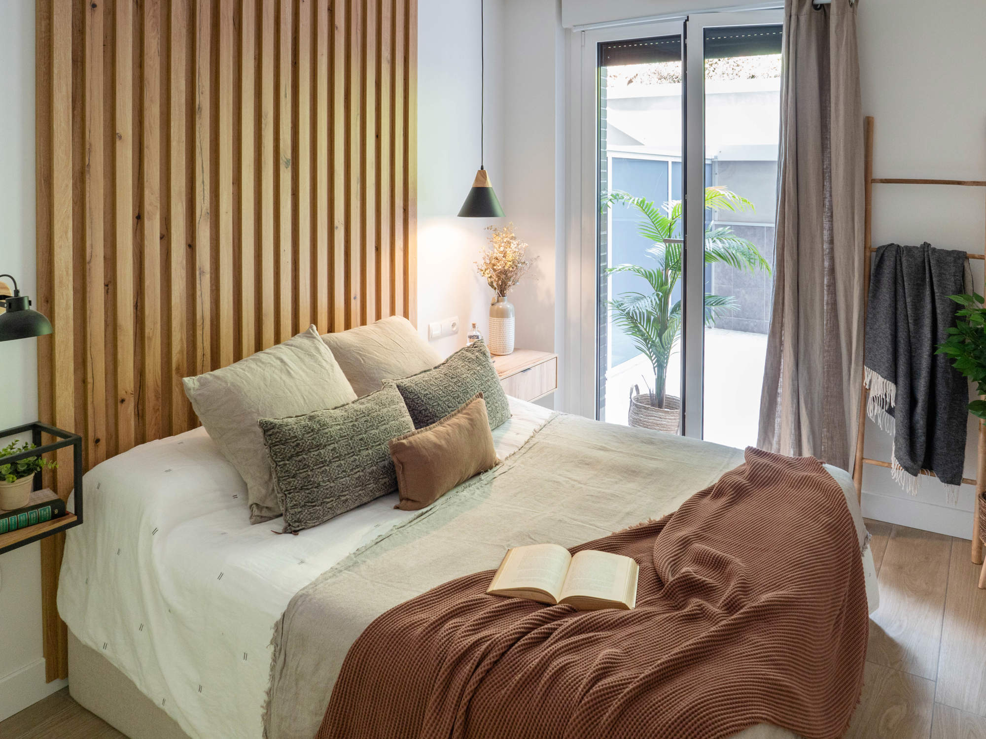 Dormitorio con cabecero de madera y mesitas de noche a ambos lados desiguales.