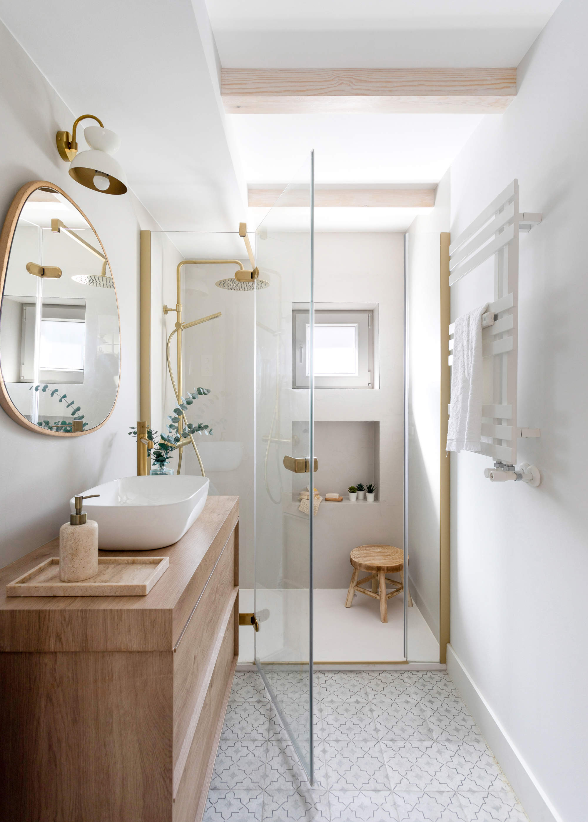 Baño con ducha con mampara y detalles en dorado.