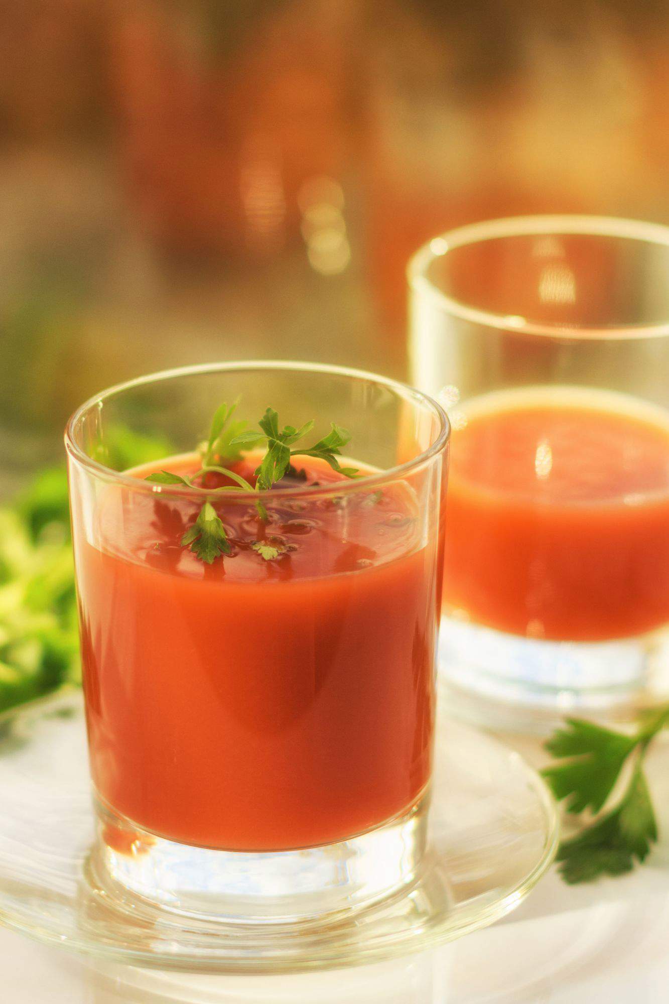 Un zumo de tomate en un vaso sencillo de cristal con perejil.