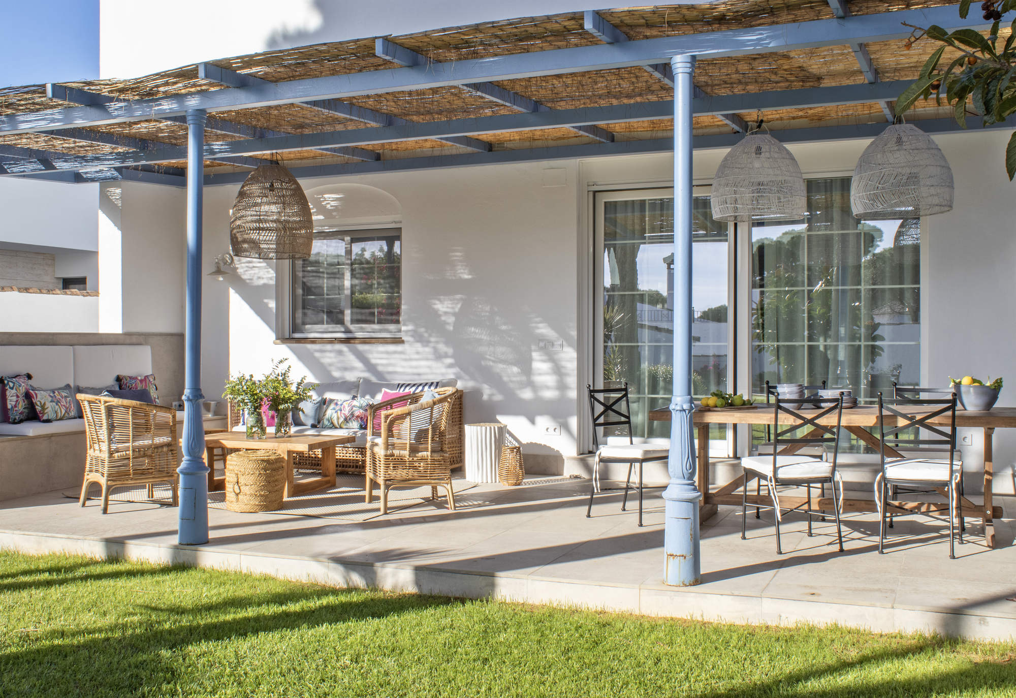 Un jardín lleno de vida con porche con techo de cañas de bambú, chill out y mesa de comedor