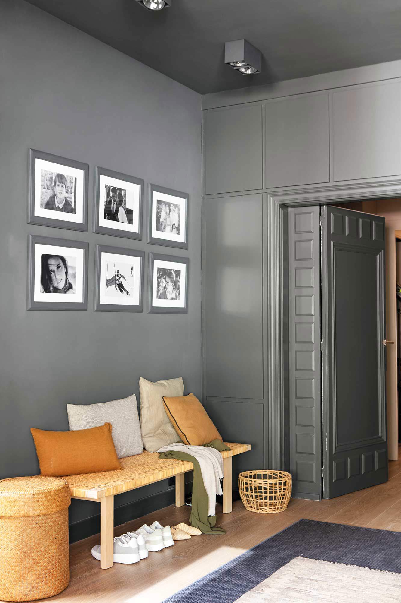 Recibidor con banco y pared decorada con una composición de fotografías en blanco y negro.
