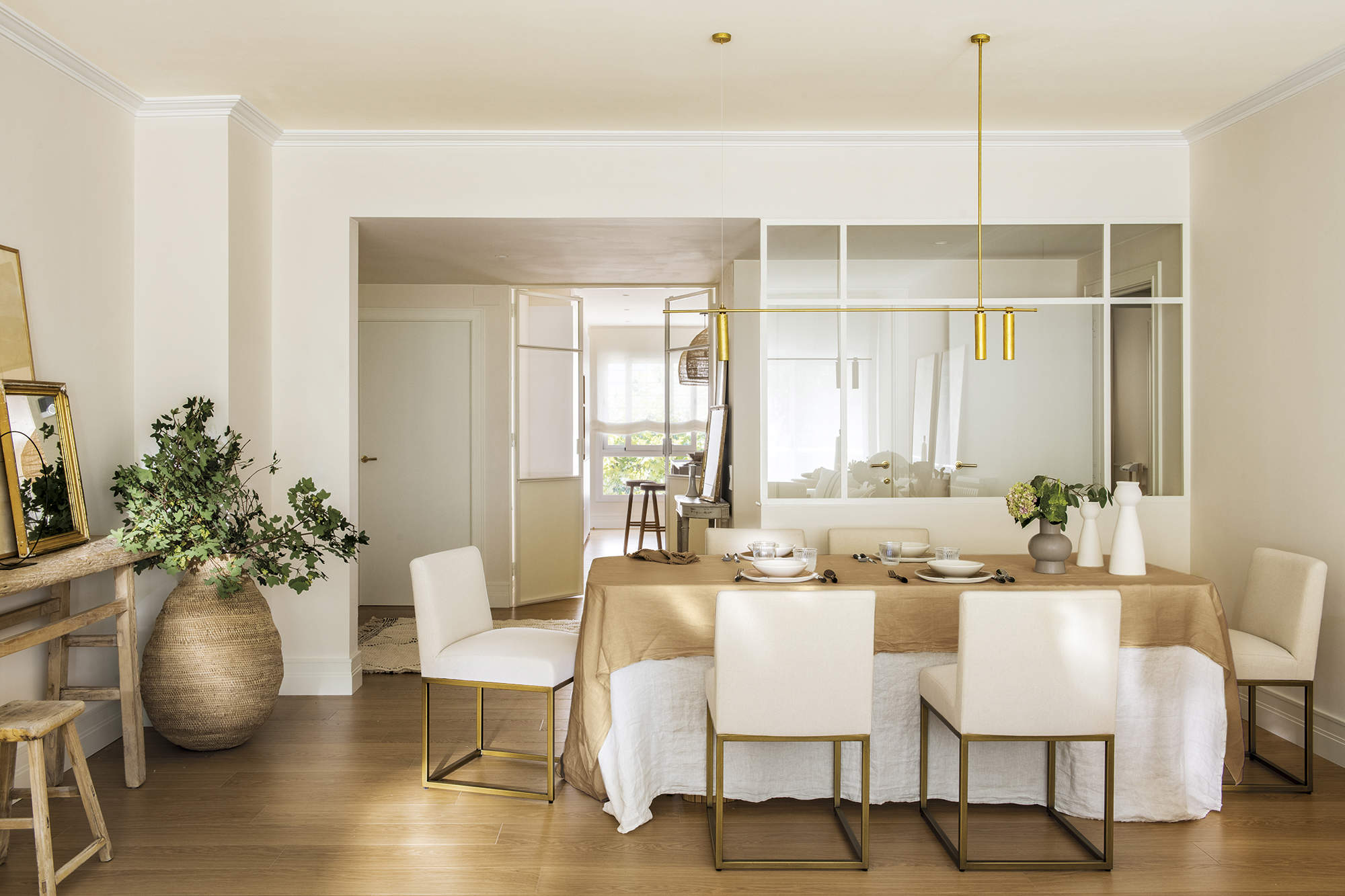 Comedor, recibidor, sillas blancas tapizadas, mantel blanco, mantel beige, pared de cristal.