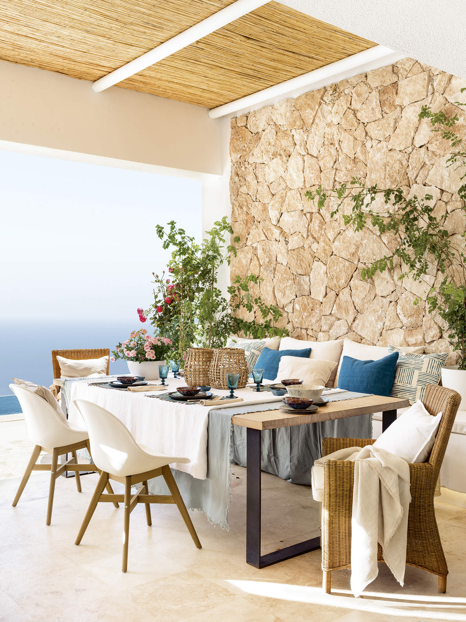 Comedor exterior de estilo mediterráneo con porche y pared de piedra caliza