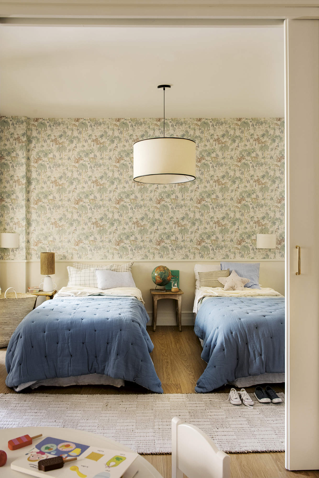 Dormitorio, cama individual, colcha azul, empapelado, lámpara de techo, alfombra.