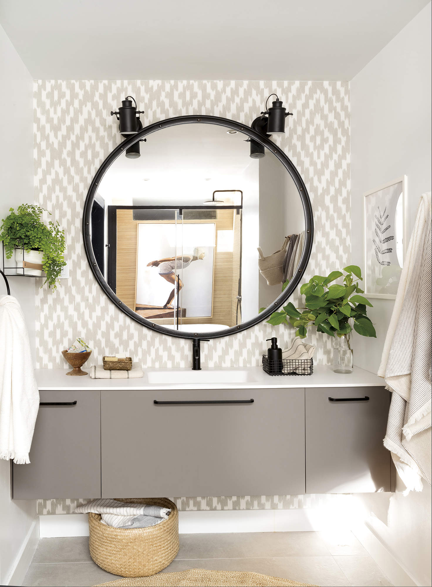 Baño con muebles grises y gran espejo con marco negro y luces a modo tocador de la casa de Paula Duarte.