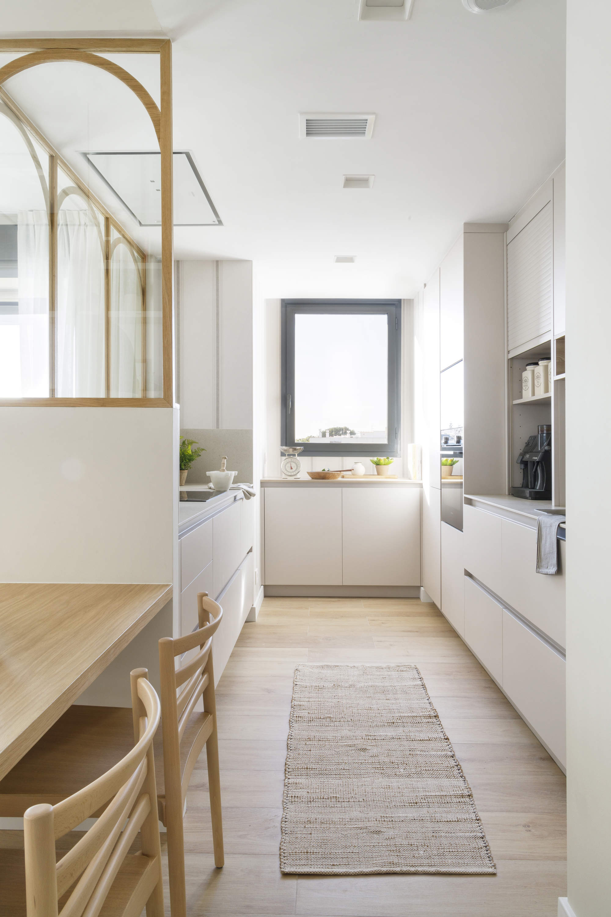 Una cocina estrecha de color blanco con elementos de madera.