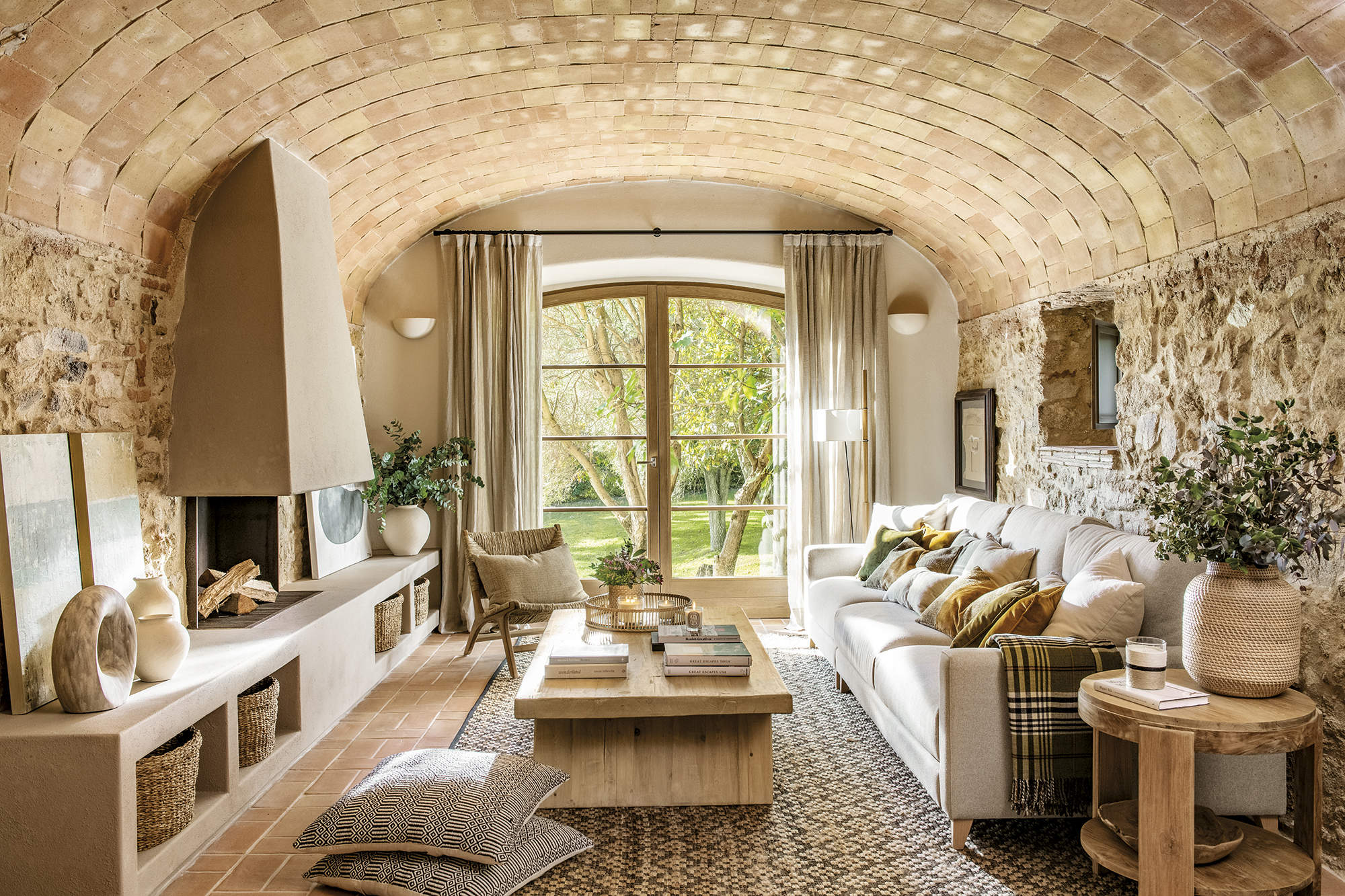 Salón cálido con paredes de piedra y suelo de barro decorado por Pia Capdevila