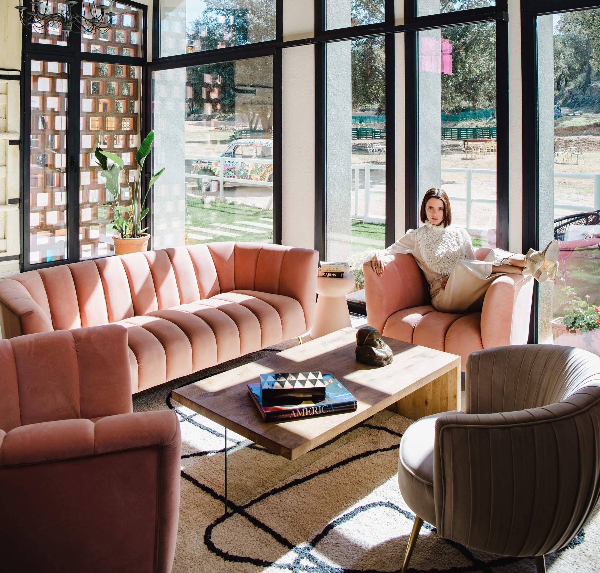 Macarena Gómez en su salón con sofás rosas y mesita de centro de madera.