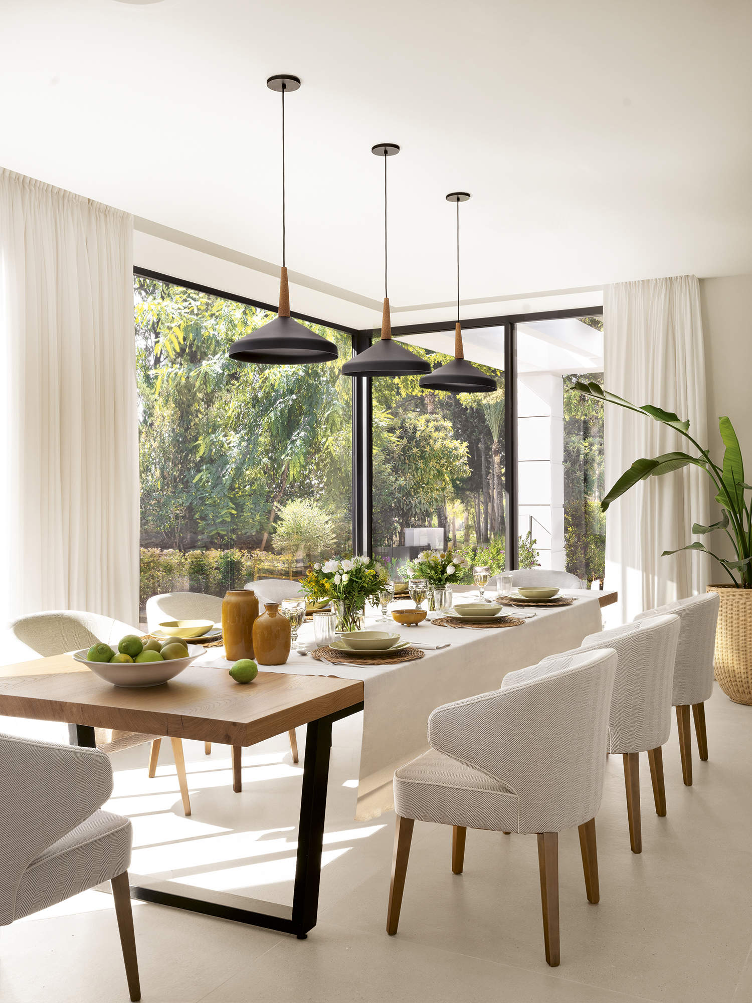 Comedor con suelo de gres, mesa rectangular de madera y sillas blancas tapizadas, plata, lámparas de techo