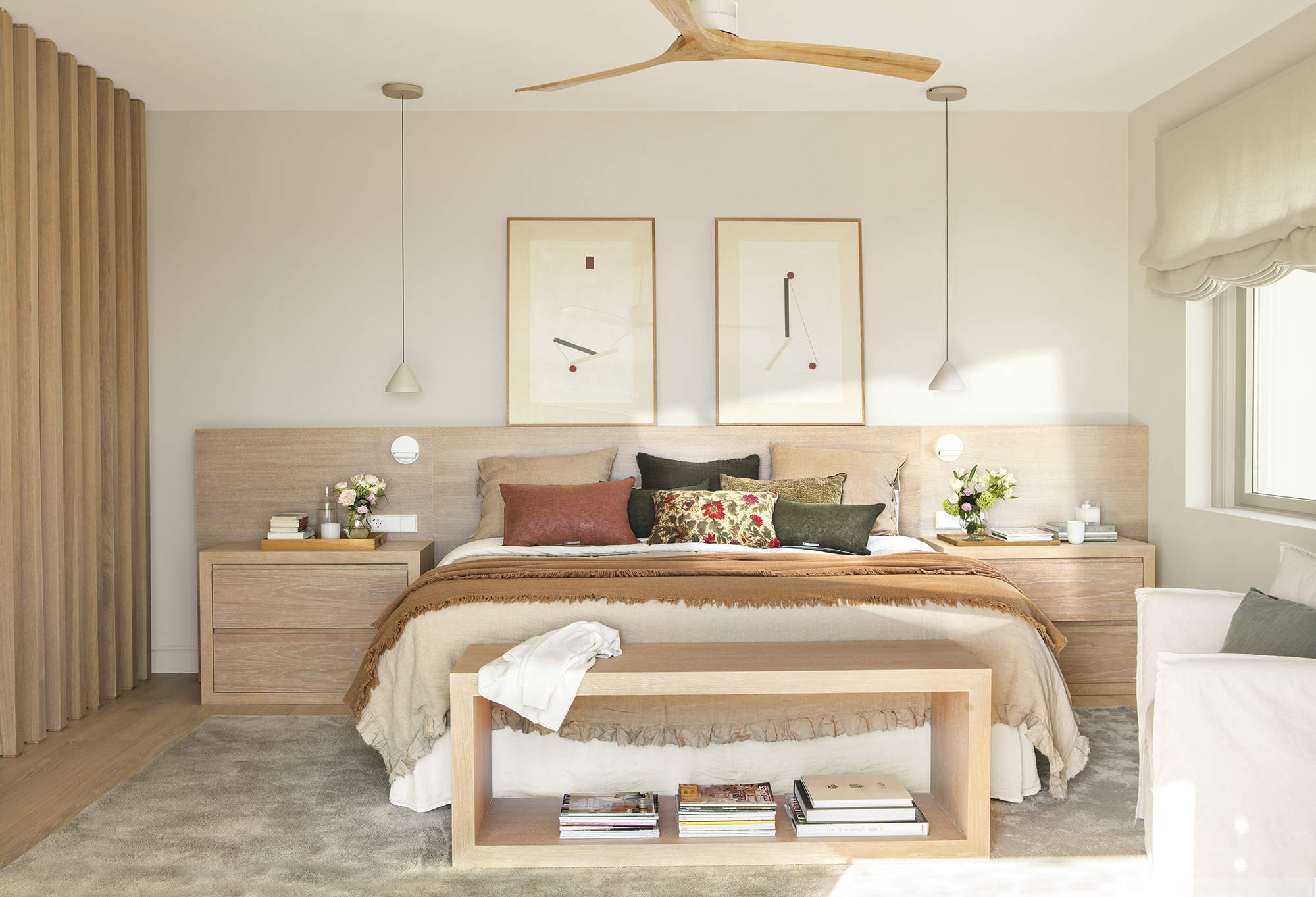 dormitorio principal con cabecero de obra, cuadros, ropa de cama beige y marrón, separador de madera y alfombra
