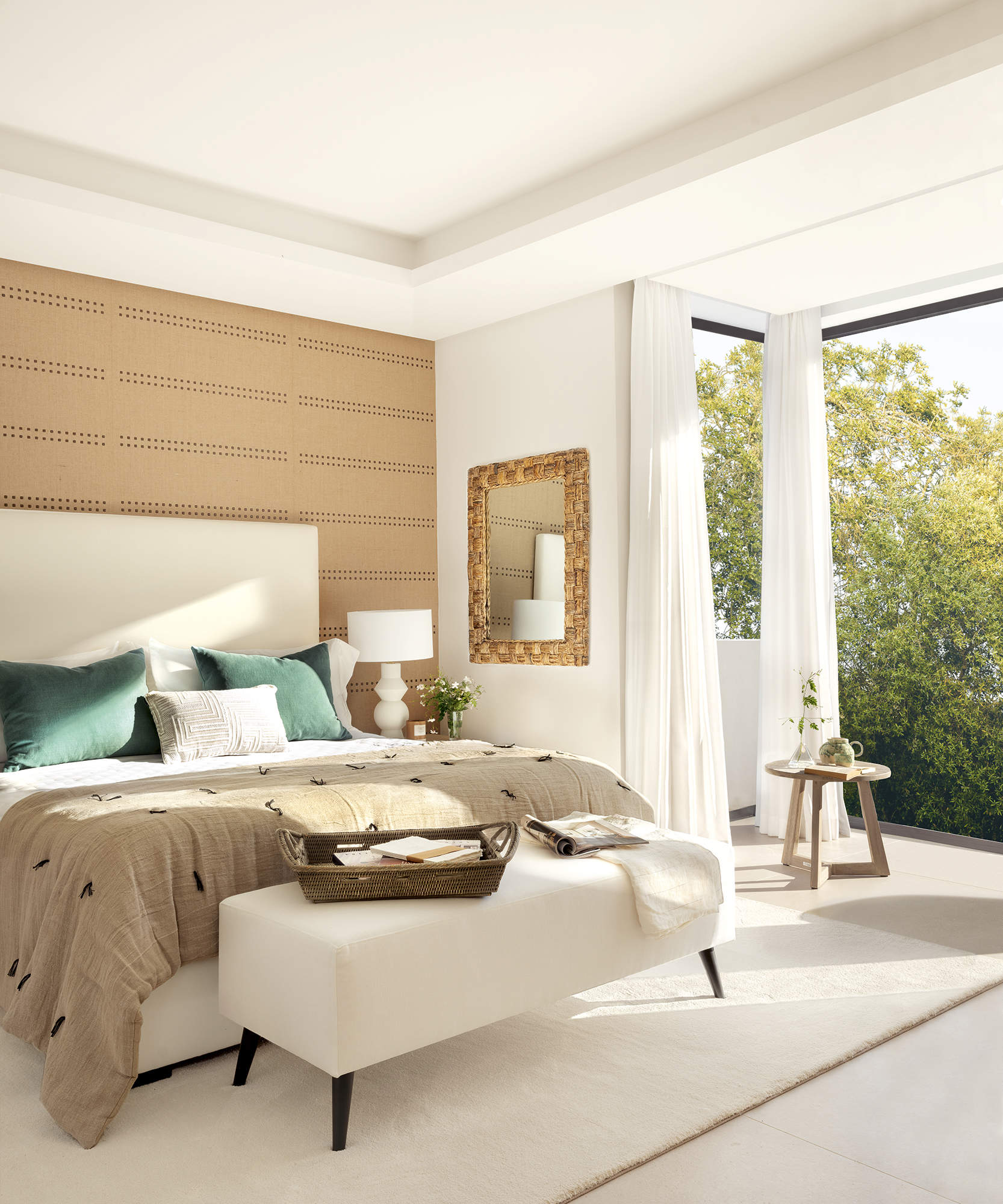 Dormitorio principal con gran ventanal, suelo de gres, pared empapelada, espejo, cabezal tapizado, alfombra blanca
