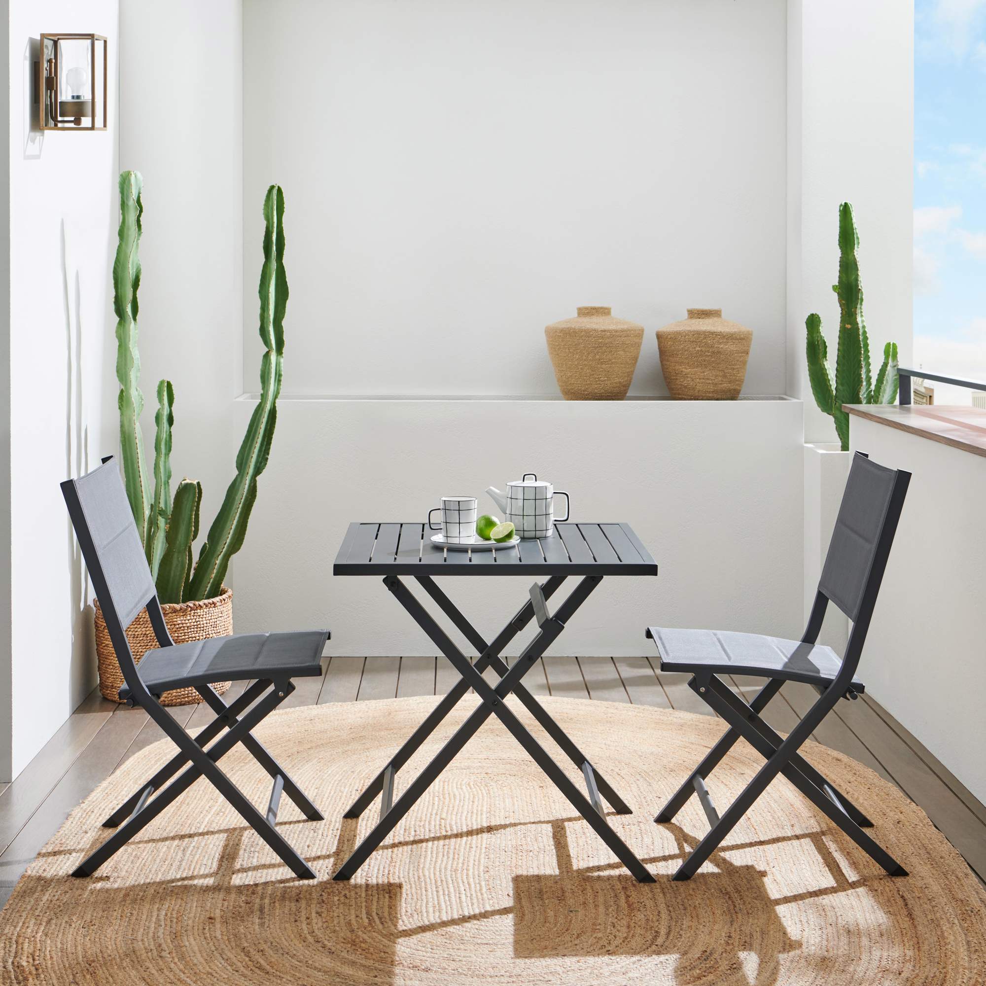 Terraza pequeña con mesa y sillas plegables en color oscuro.