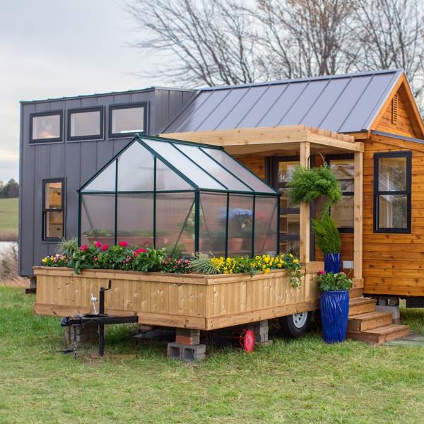 Una mini casa prefabricada de apenas 30 m2 con cocina con barra, un porche apetecible ¡y hasta invernadero ecológico!