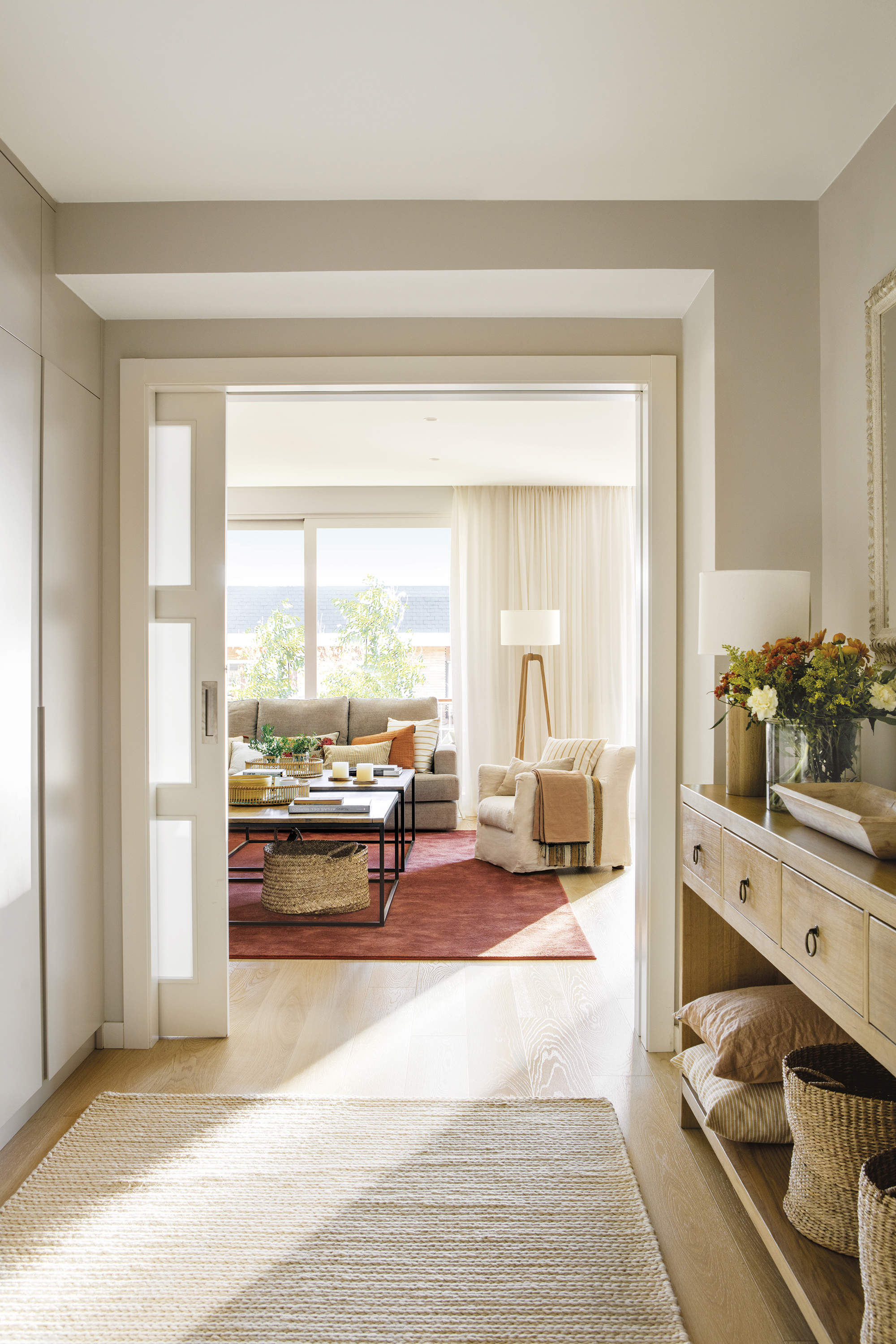 recibidor con mueble de madera y armario a medida, puerta corredera con salón al fondo con alfombra color morado