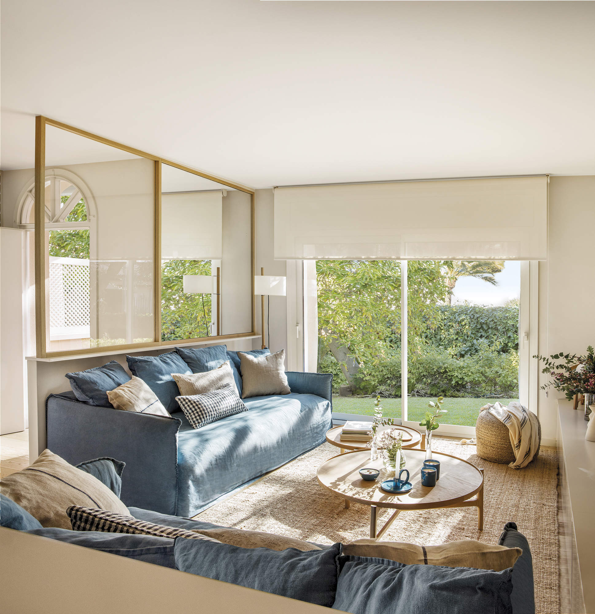 Salón con sofá azul, cerramiento de cristal y alfombra de fibras