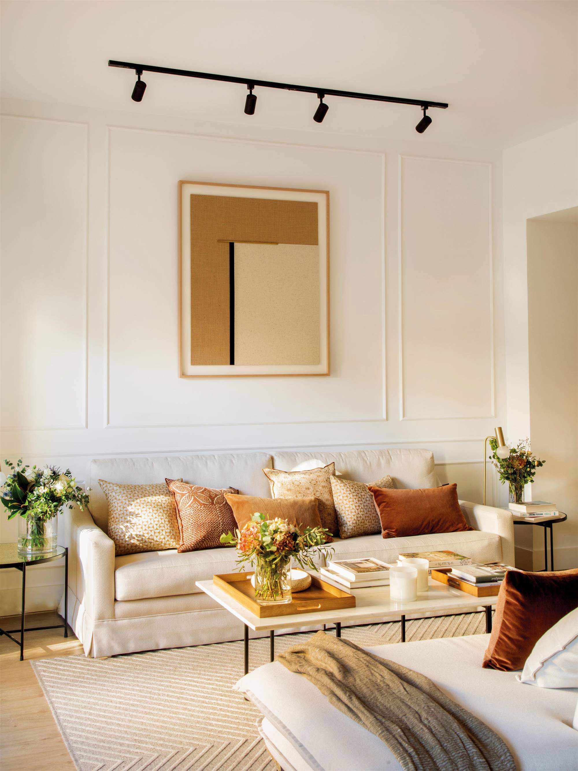 Salón con sofá, molduras en pared y cuadro con iluminación.