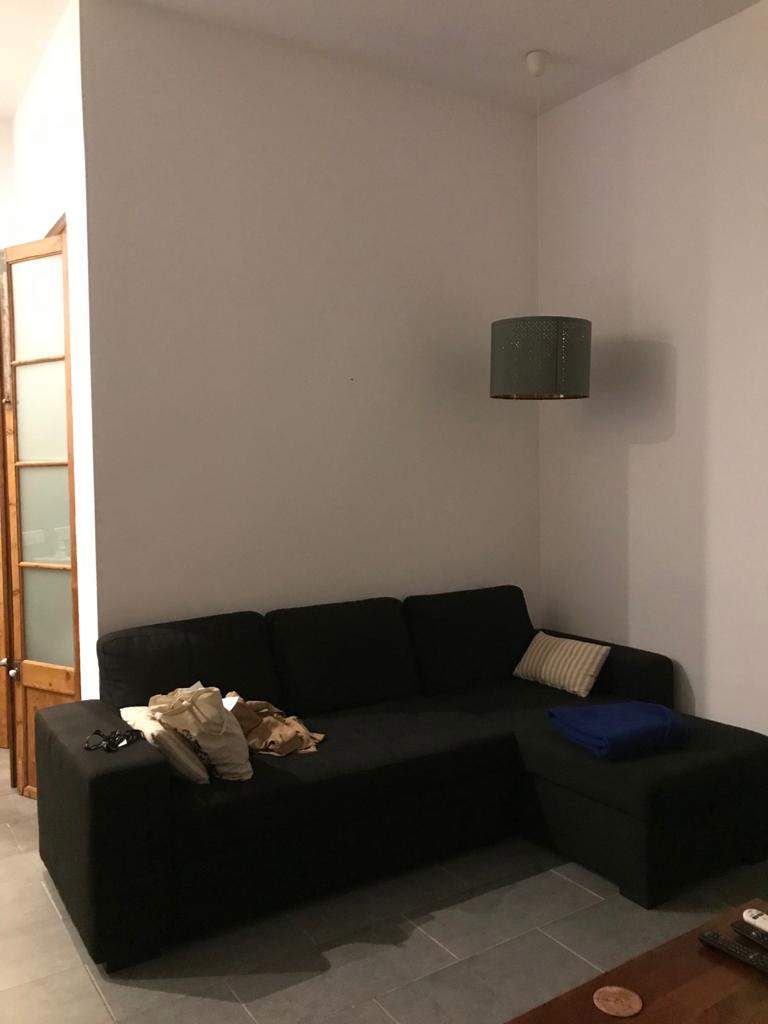 El sofá y la lámpara de pie del salón, de tonos oscuros y diseño simple.
