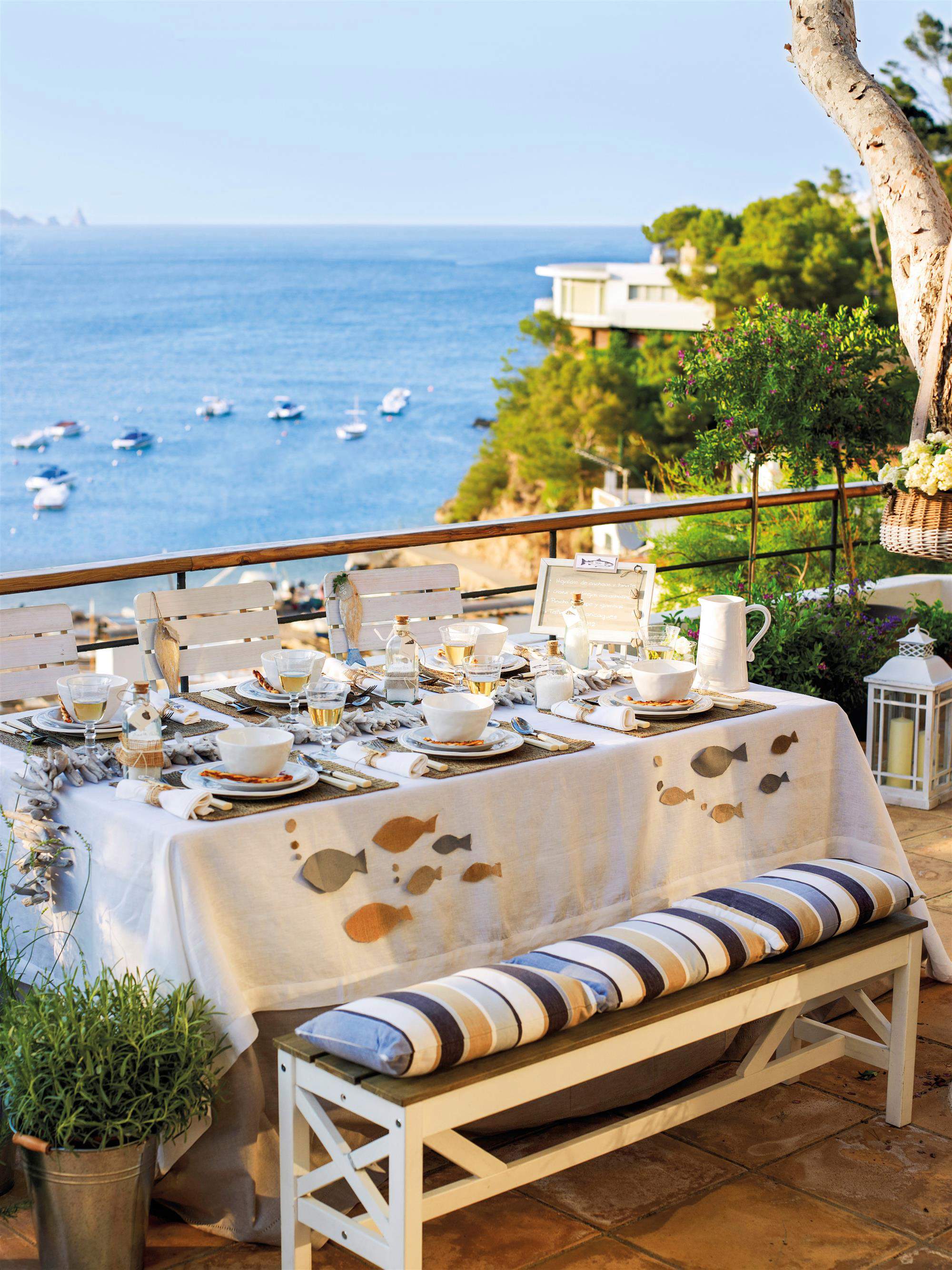 Balcón delante del mar con mesa blanca con banco.