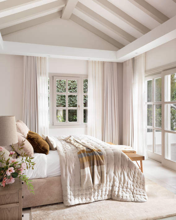 Dormitorio blanco con cama grande y textiles en tonos neutros