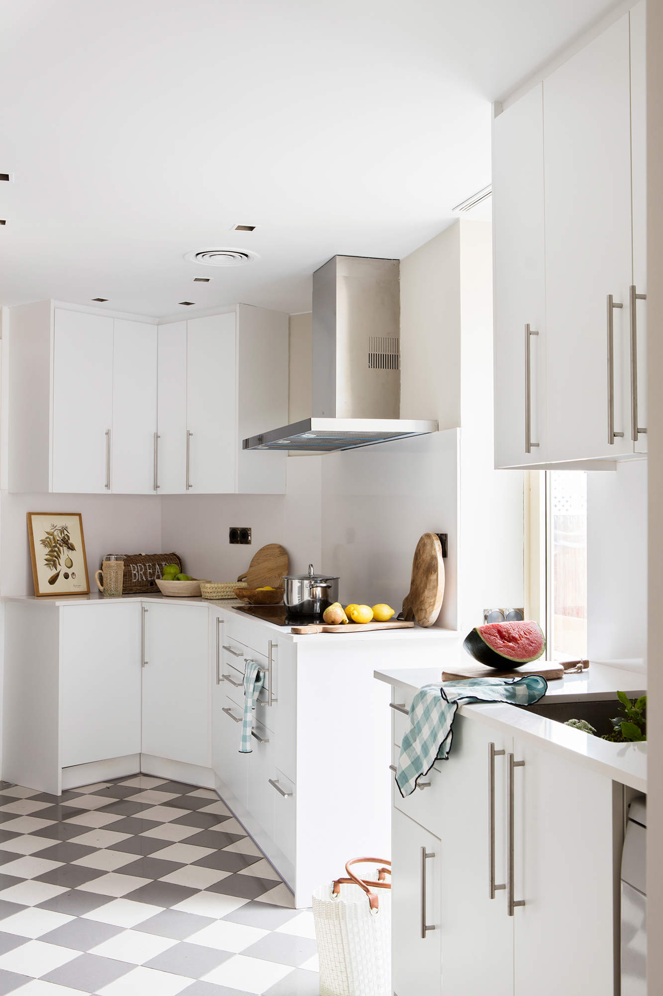 Cocina blanca moderna con paredes lisas y suelo con baldosas en blanco y gris colocadas en damero.