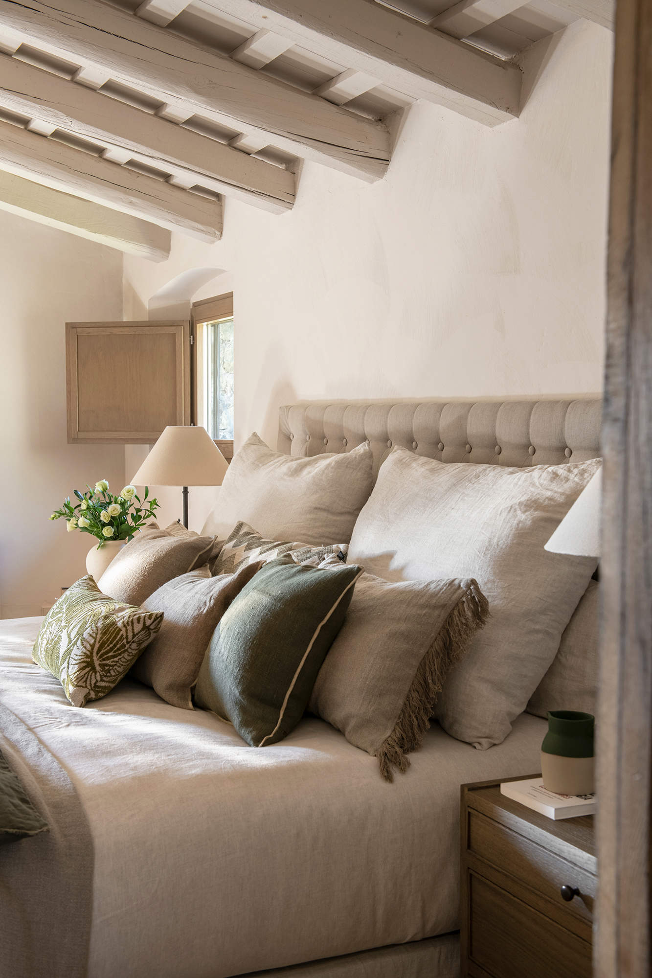 Dormitorio de estilo clásico con vigas de madera en el techo, pintadas en blanco.