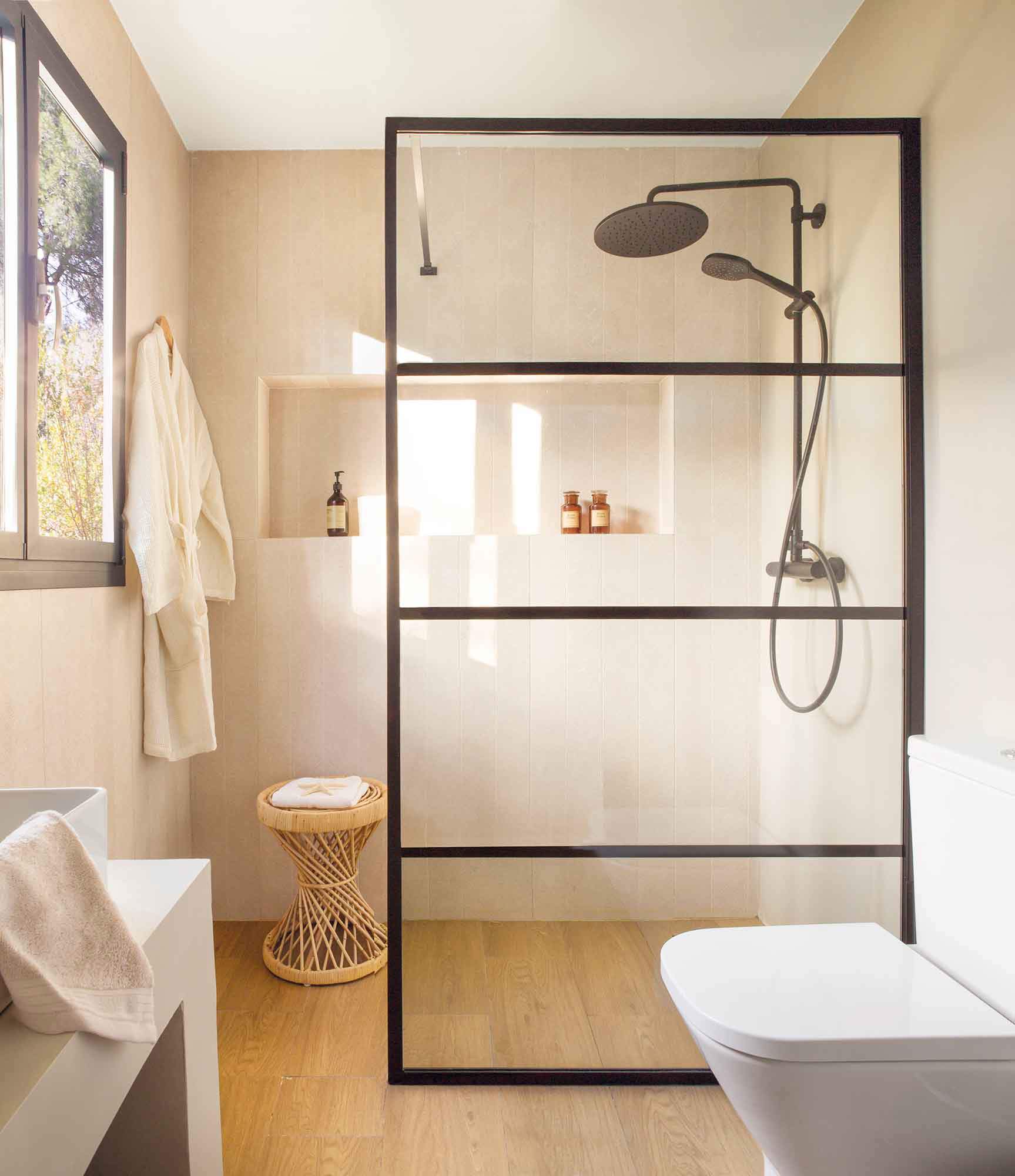 Baño moderno con suelo de madera, ducha con grifería negra y mampara. 