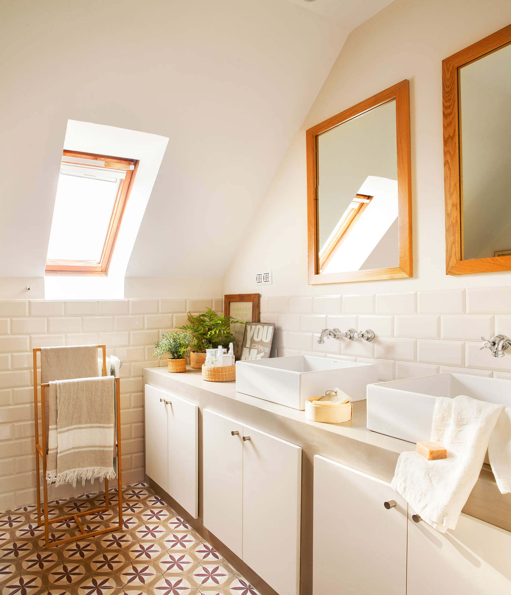 Baño con azulejos tipo vinílico, espejos de madera y lavabo doble. 