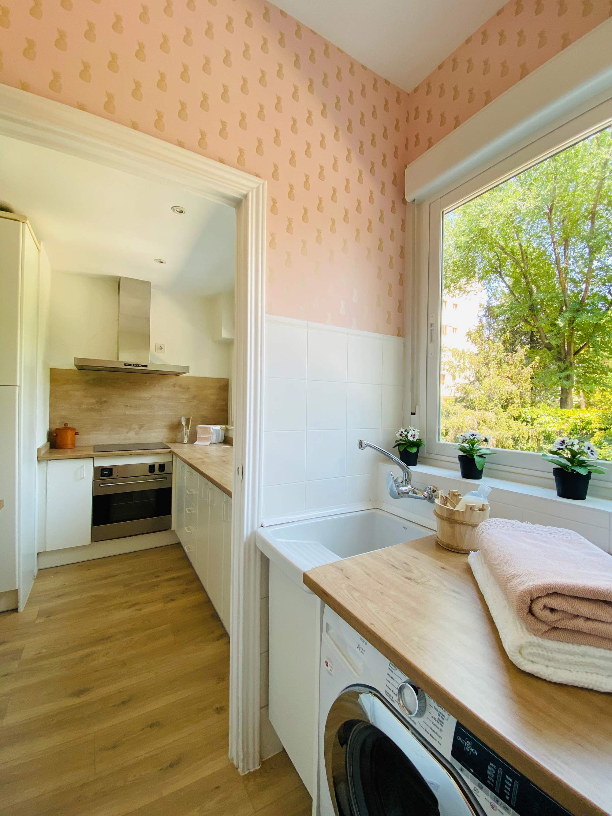 Cocina con arrimadero, zona de lavado, papel pintado rosa y encimeras, de madera.