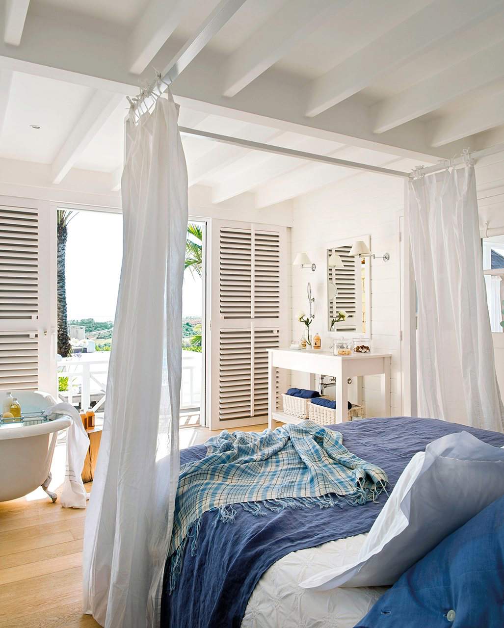 Dormitorio con cama de dosel y textil en tonos blancos y azules.