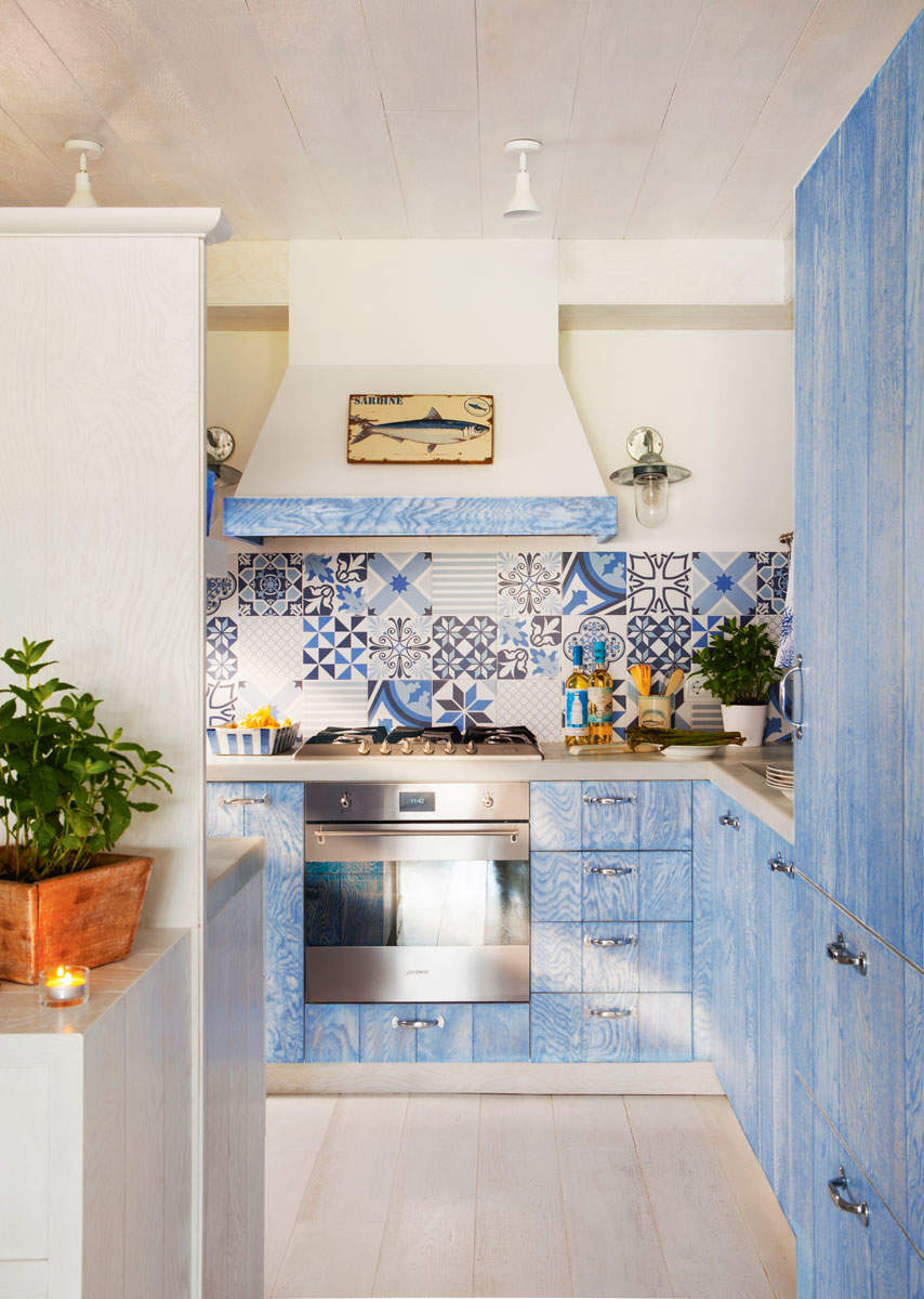 Cocina de estilo marinero con muebles azules y azulejos en el antepecho, azules.