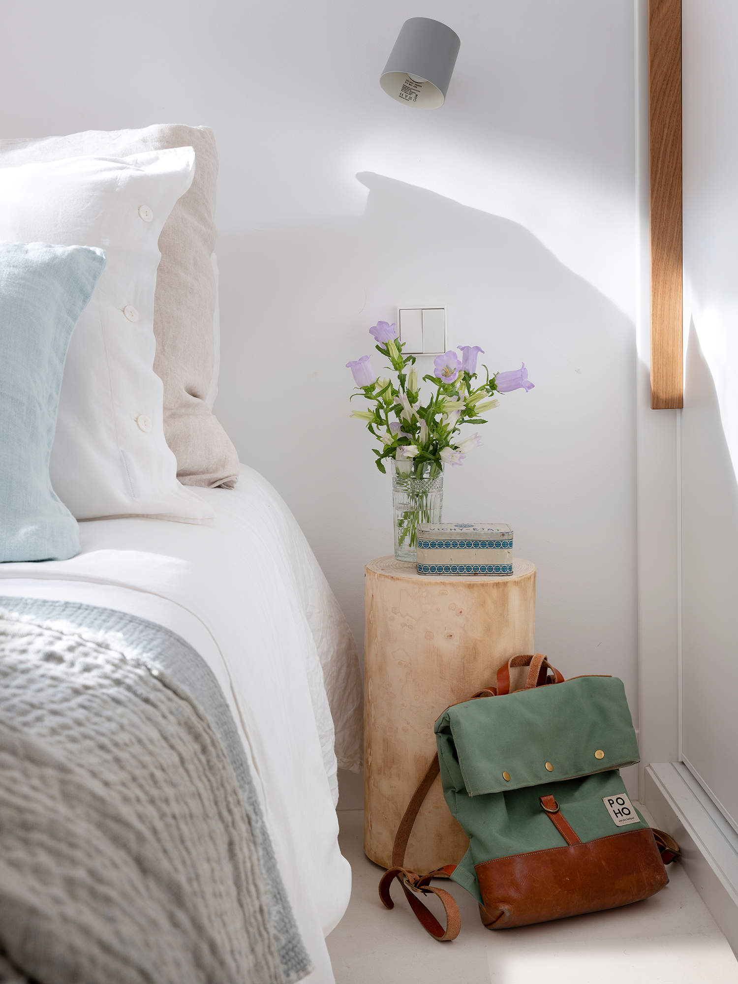 Dormitorio blanco con mesita de tronco de madera.