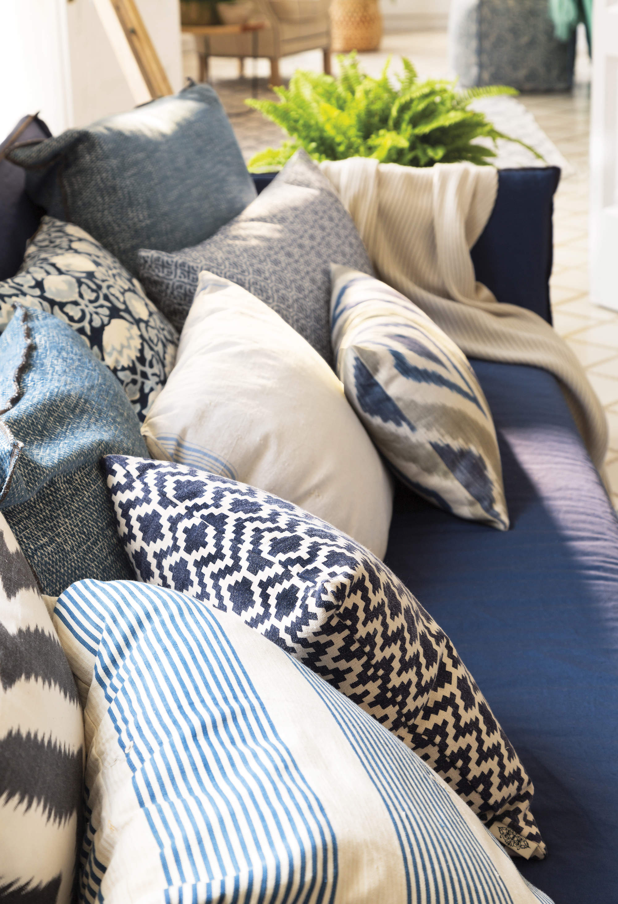 Salón con sofá azul decorado con sofás azules de distintos tamaños y estampados.